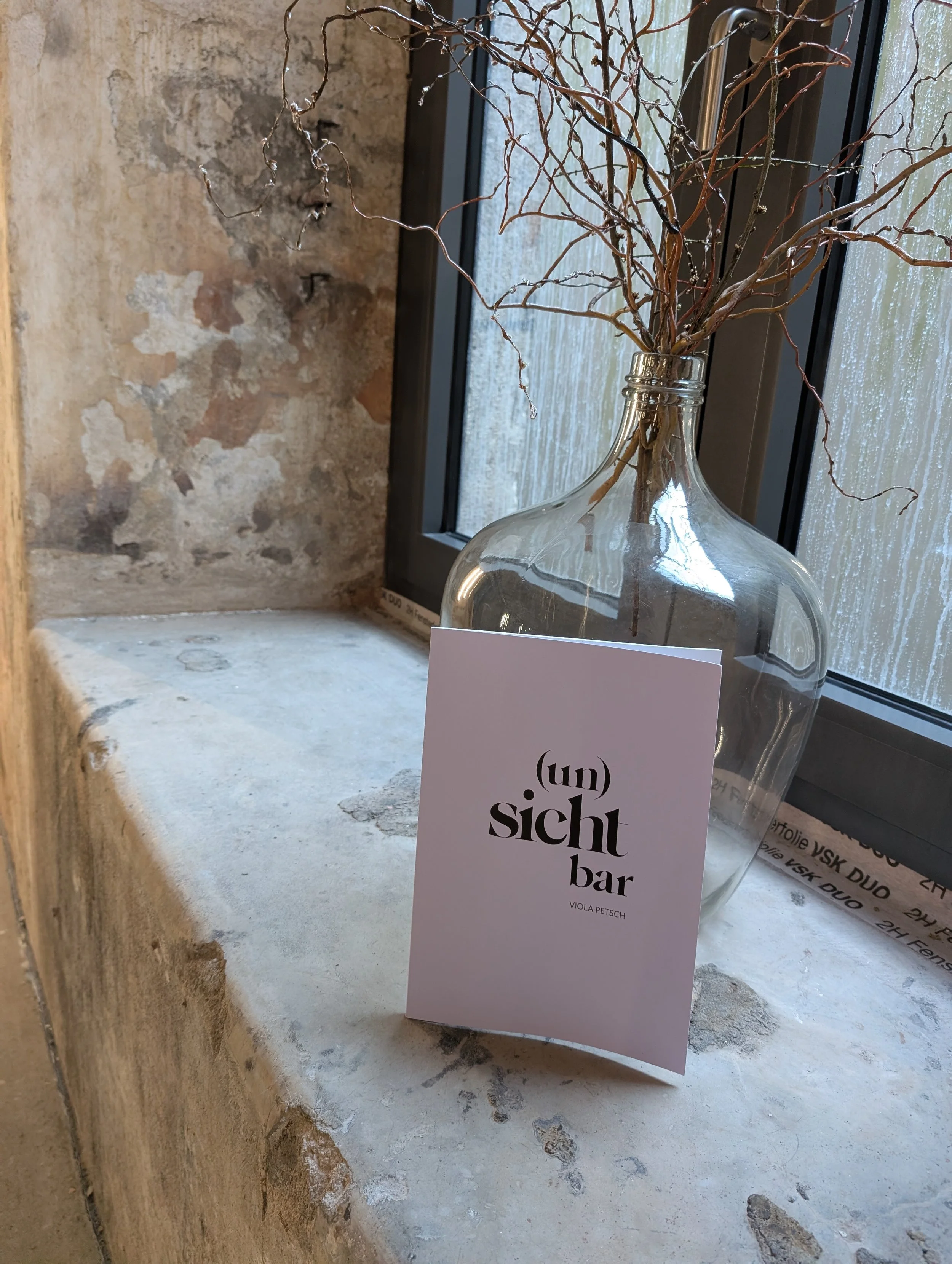 Vernissage "(un)sichtbar" in der Sektkellerei Höfer, Bildband zum Porträtprojekt von Viola Petsch lehnt vor Vase