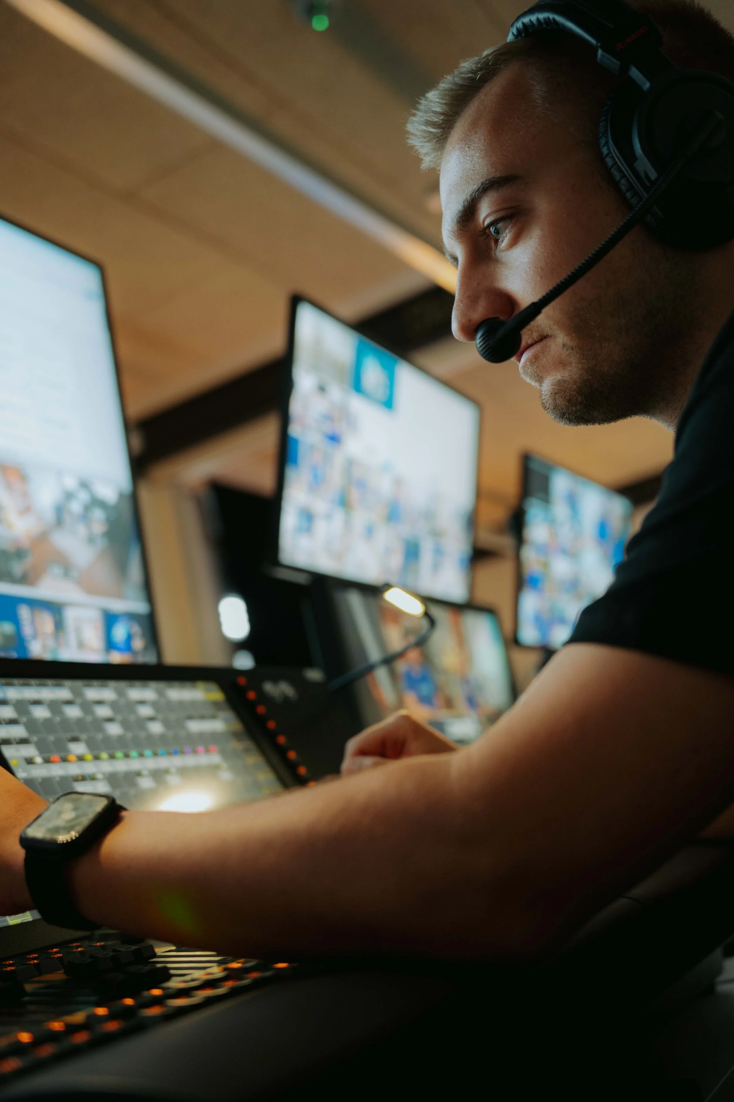 Mann mit Headset arbeitet an einer Medien-Produktion mit mehreren Bildschirmen.