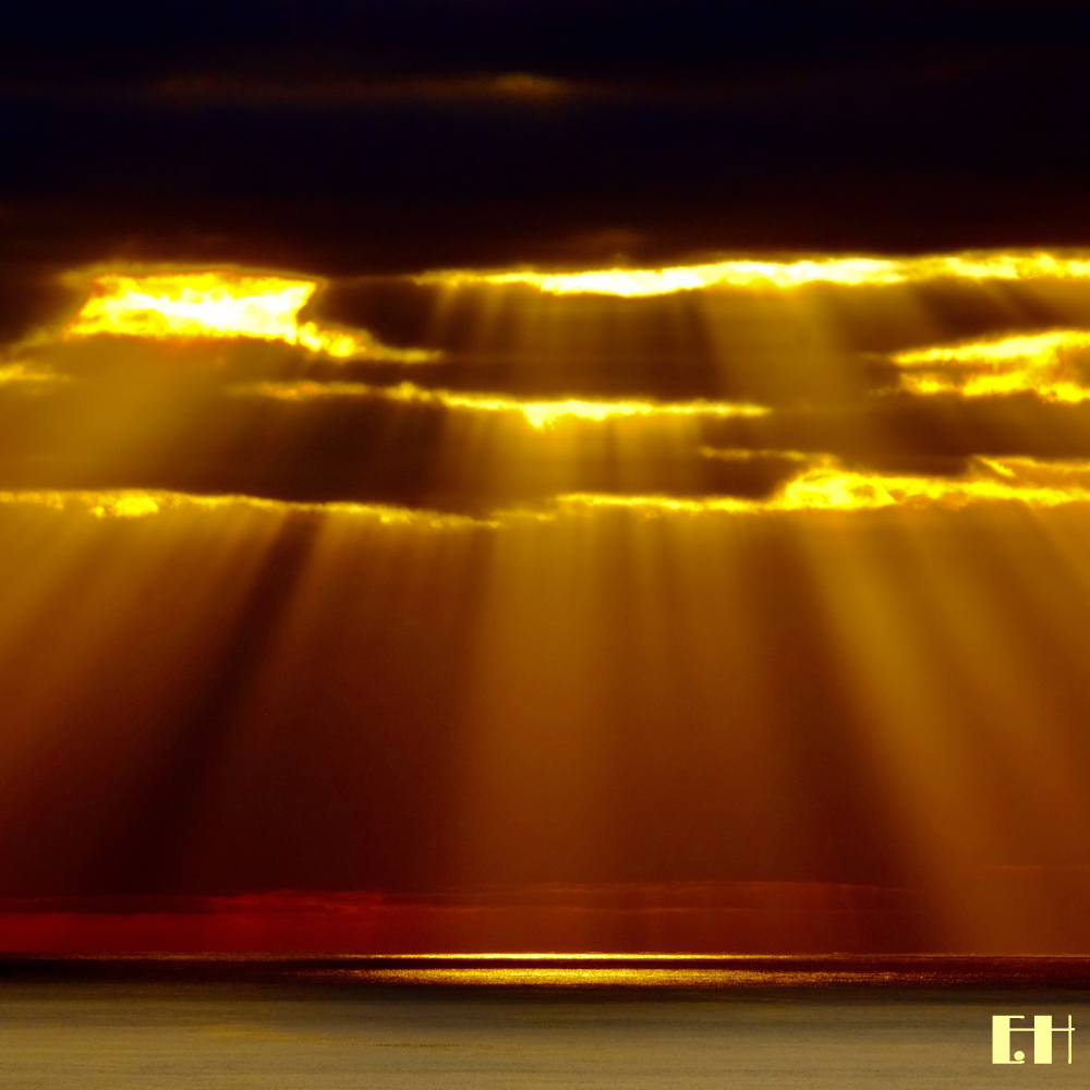 Sonnenstrahlen durchbrechen dunkle Wolken über dem Meer aus der fotografischen Serie Fluentum