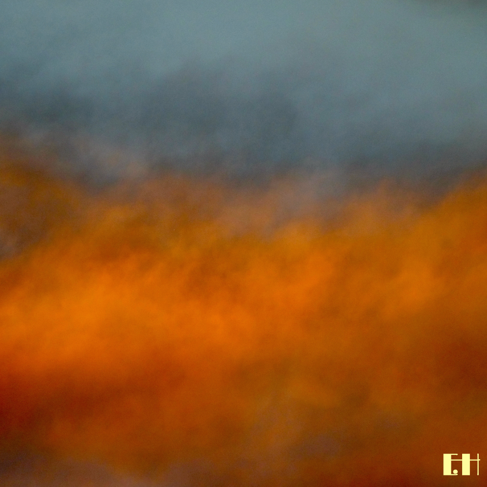 Farbige Wolken und atmosphärische Lichtstimmung in  blauen, orangefarbenen und braunen Farbtönen aus der fotografischen Serie Fluentum.