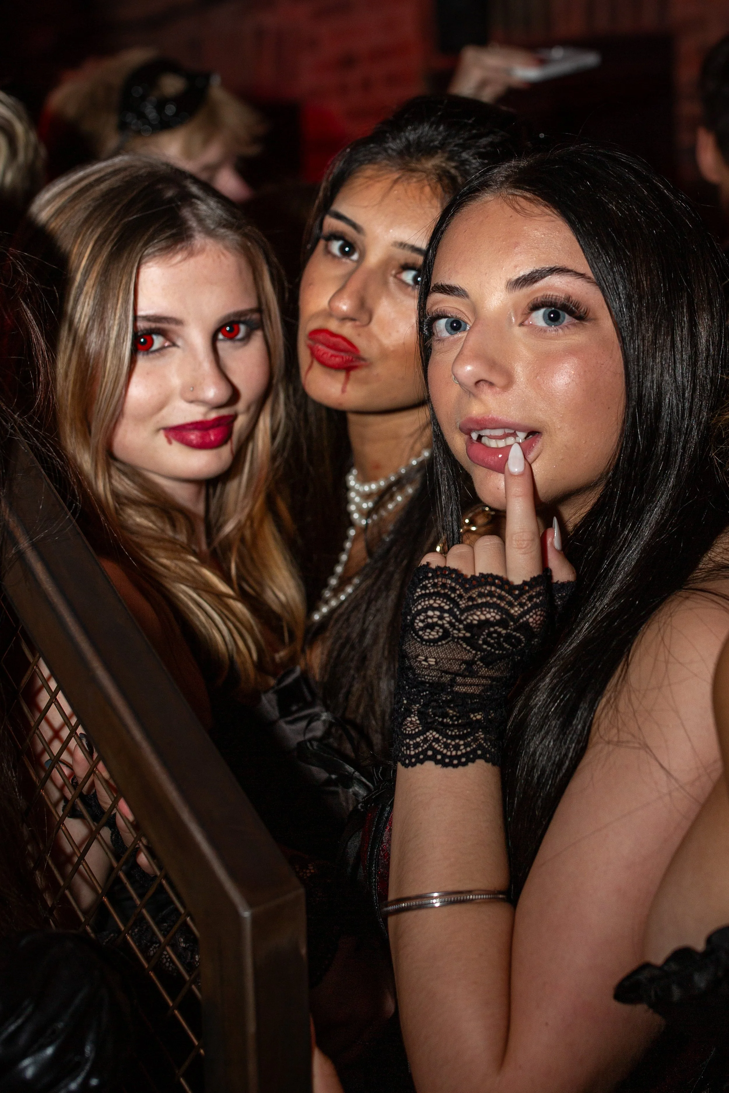 Three women dressed in Gothic style costumes with makeup, posing for the camera at a party or event.