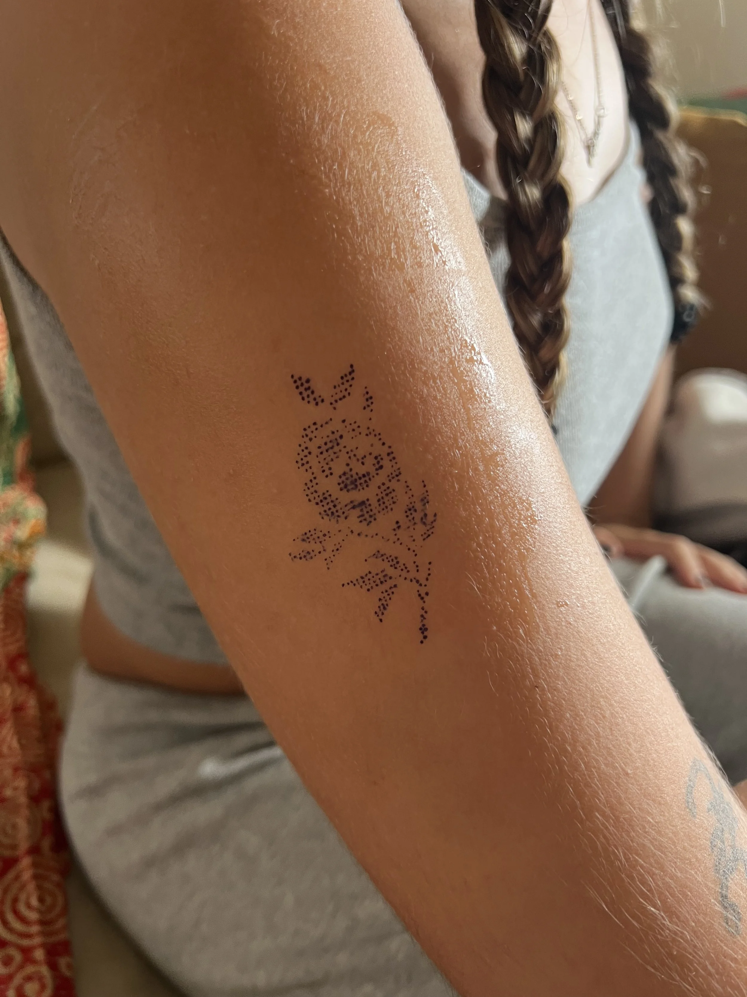 Close-up of a person's inner forearm with a temporary tattoo of the word 'LOVE' in black dots.