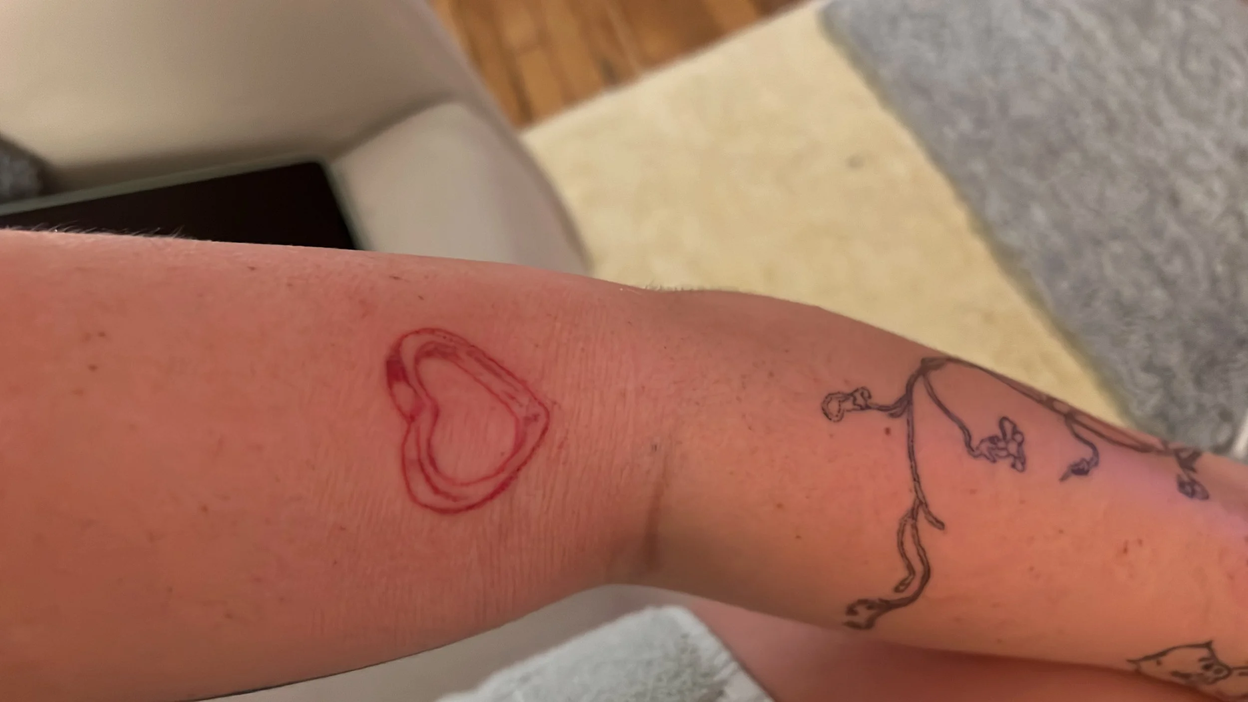 Close-up of a person's skin with a red outline of a heart tattoo.