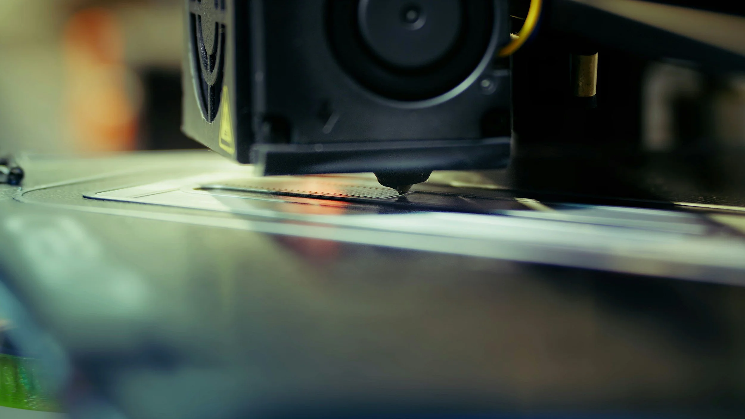 Close-up of a 3D printer extruding material onto a print bed.