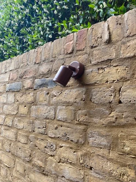 Hunza copper wall-mounted spotlight on brick garden wall, Hampstead — Hobbs Electrical Group