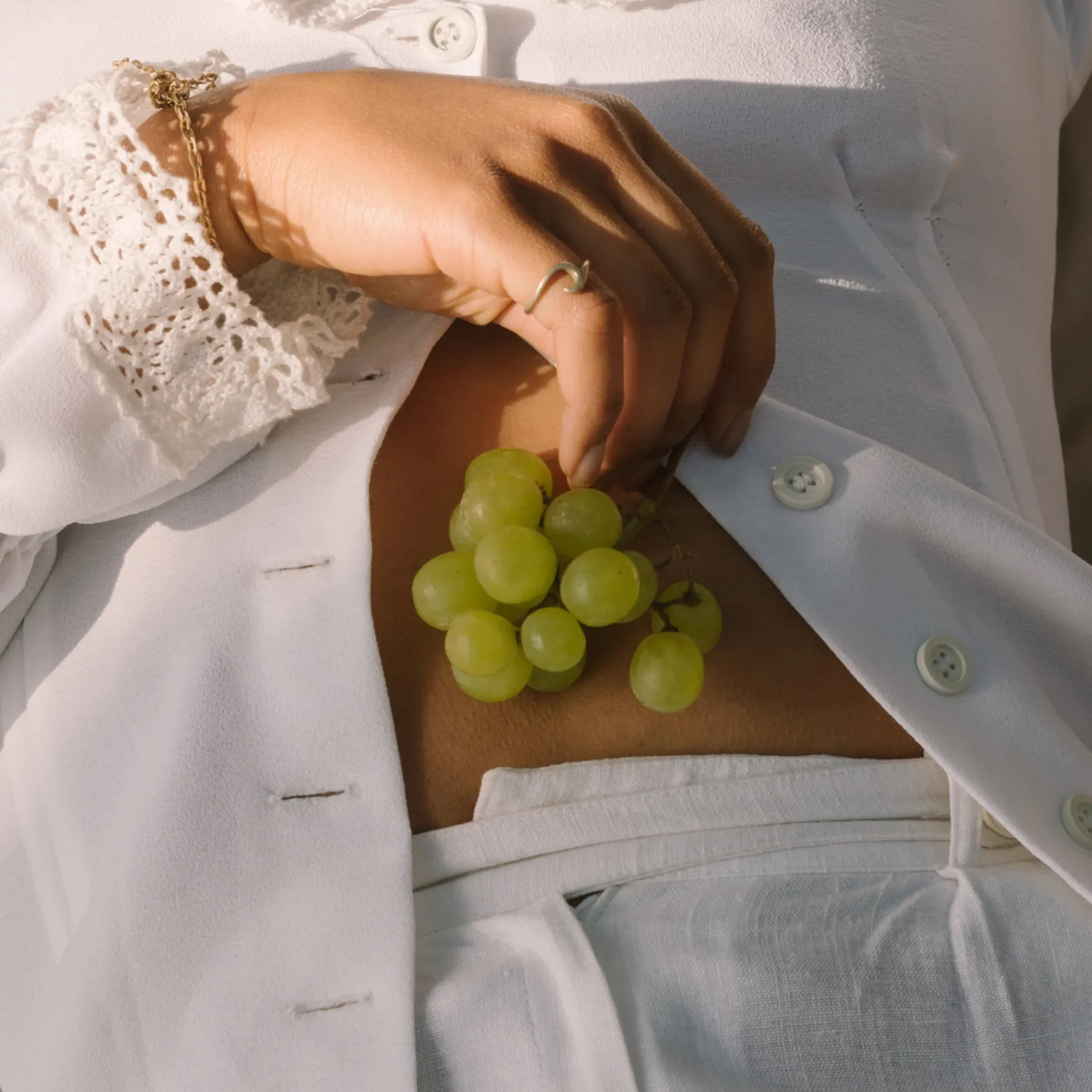Woman holding a cluster of grapes by her stomach