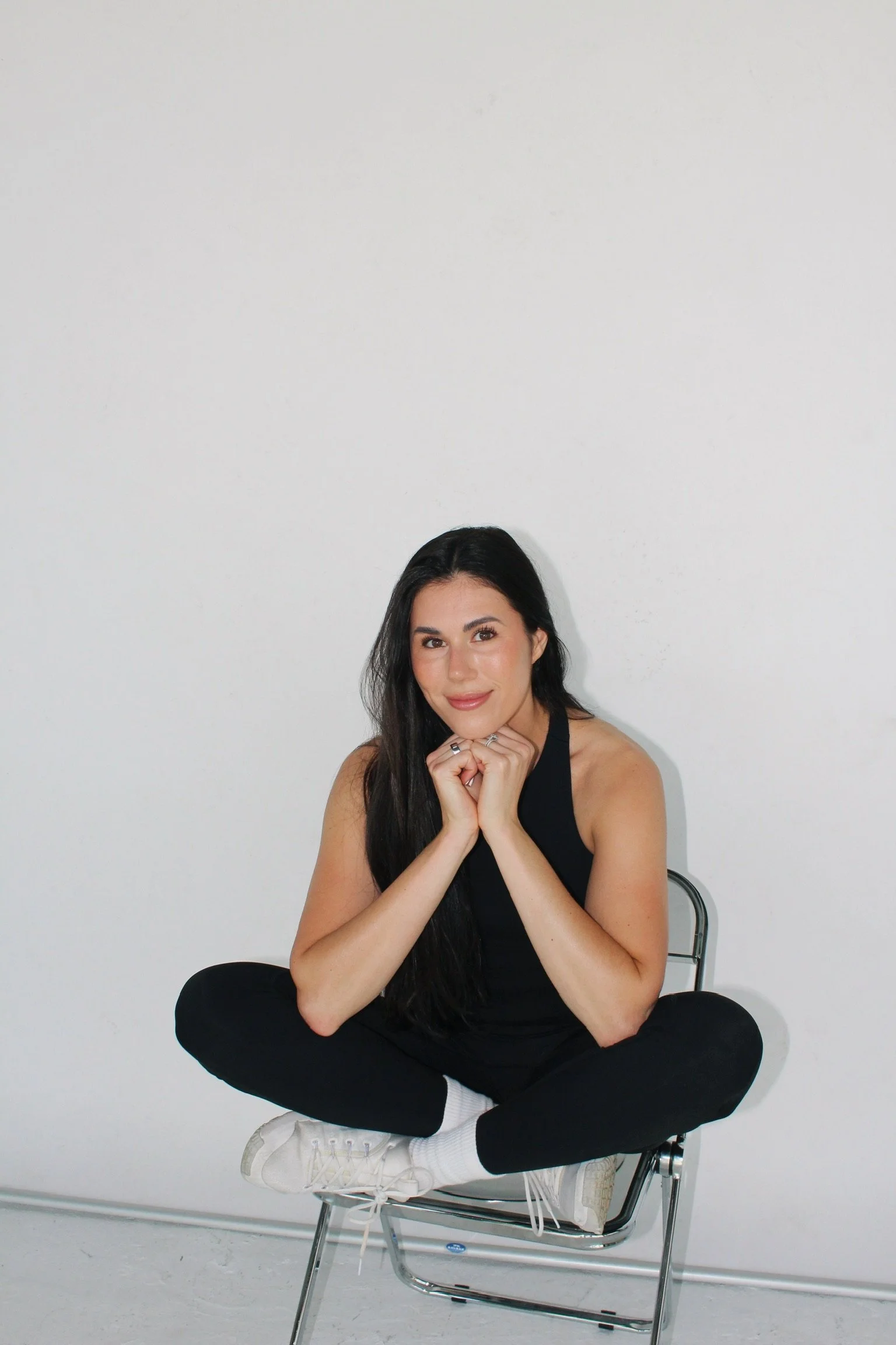  Kristen sitting cross-legged on a chair and smiling 