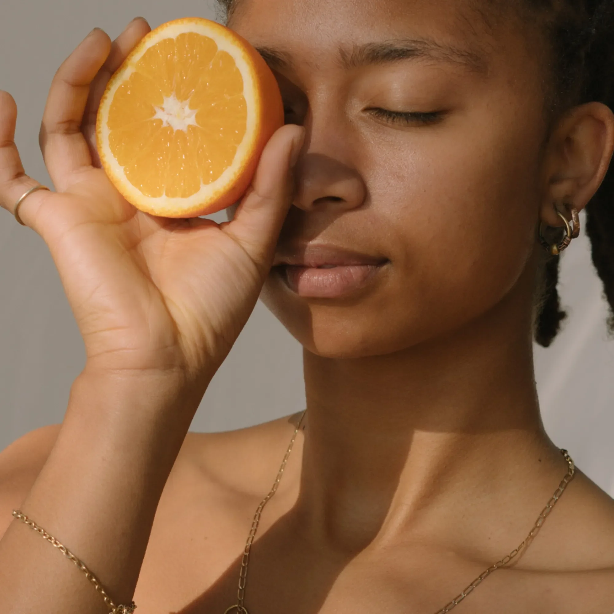 Woman holding a halved orange in front of her eye