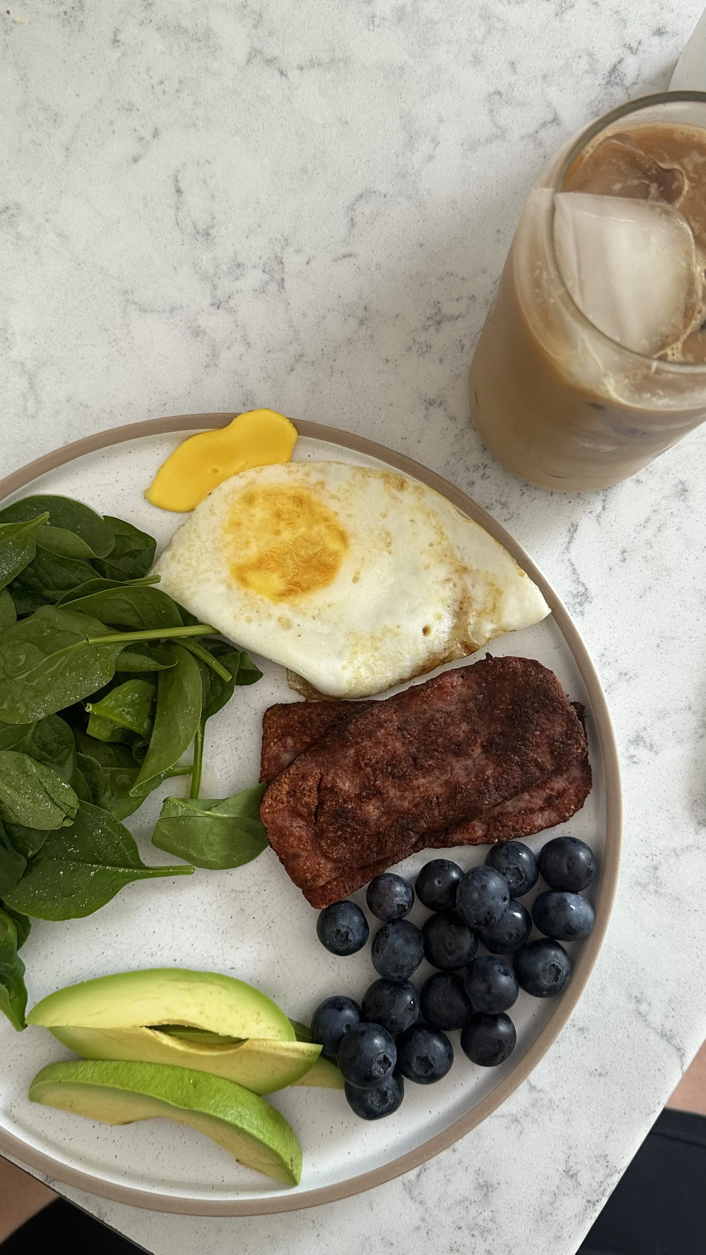 A plate with eggs, sausage, spinach and blueberries on