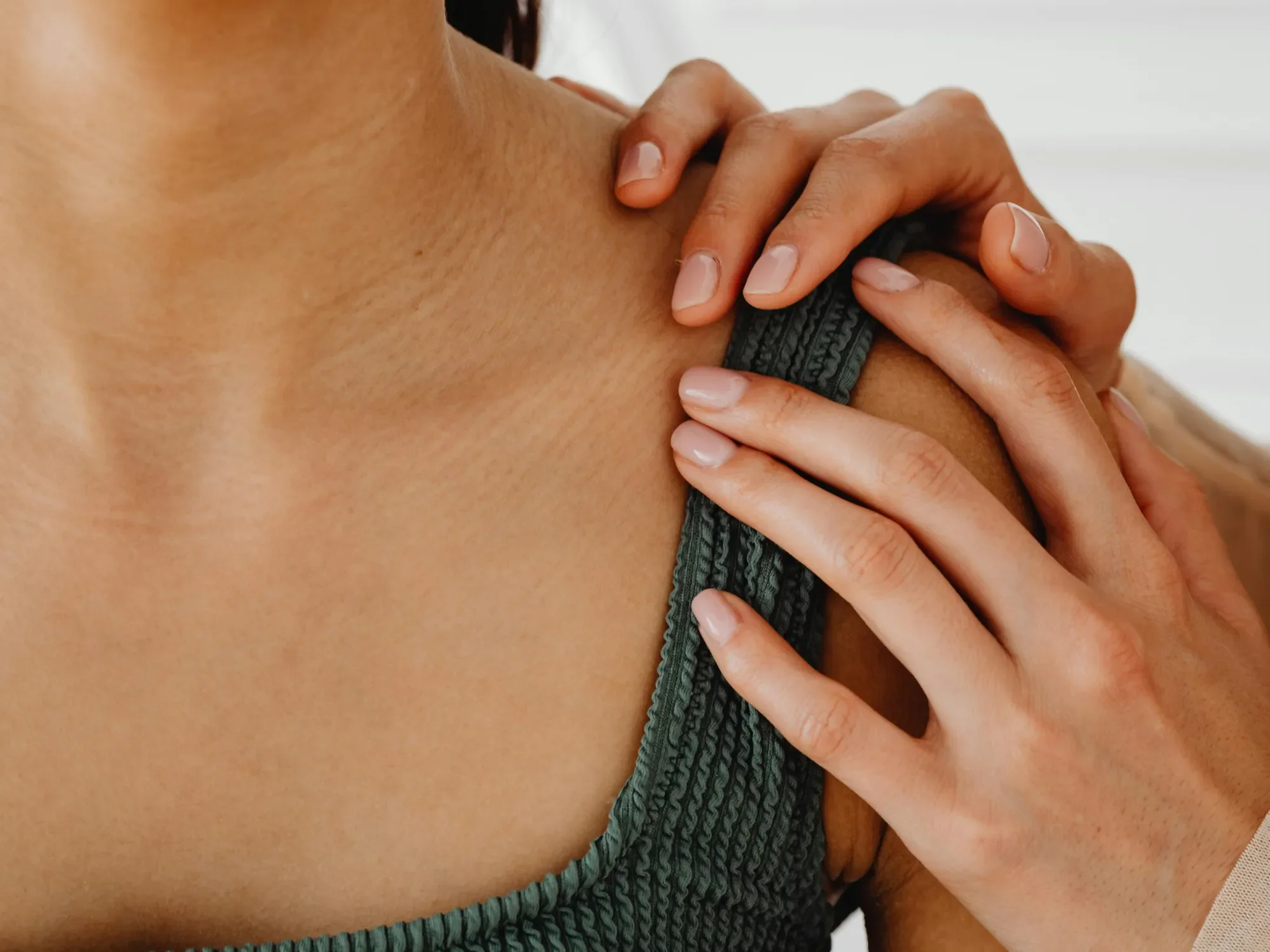 Supportive hands placed on a woman's shoulder