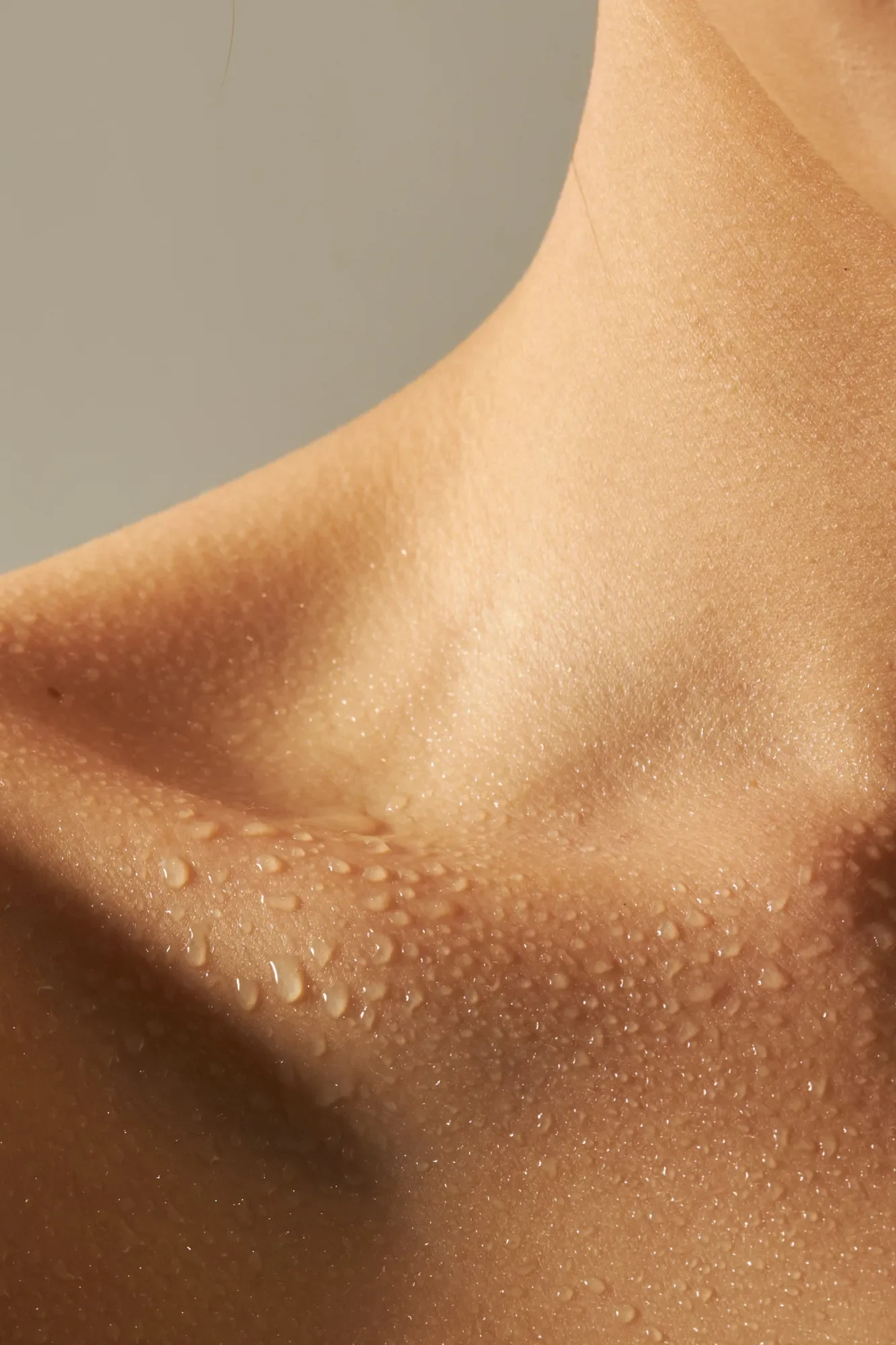 Close-up of a woman's clavicle dripping with water droplets