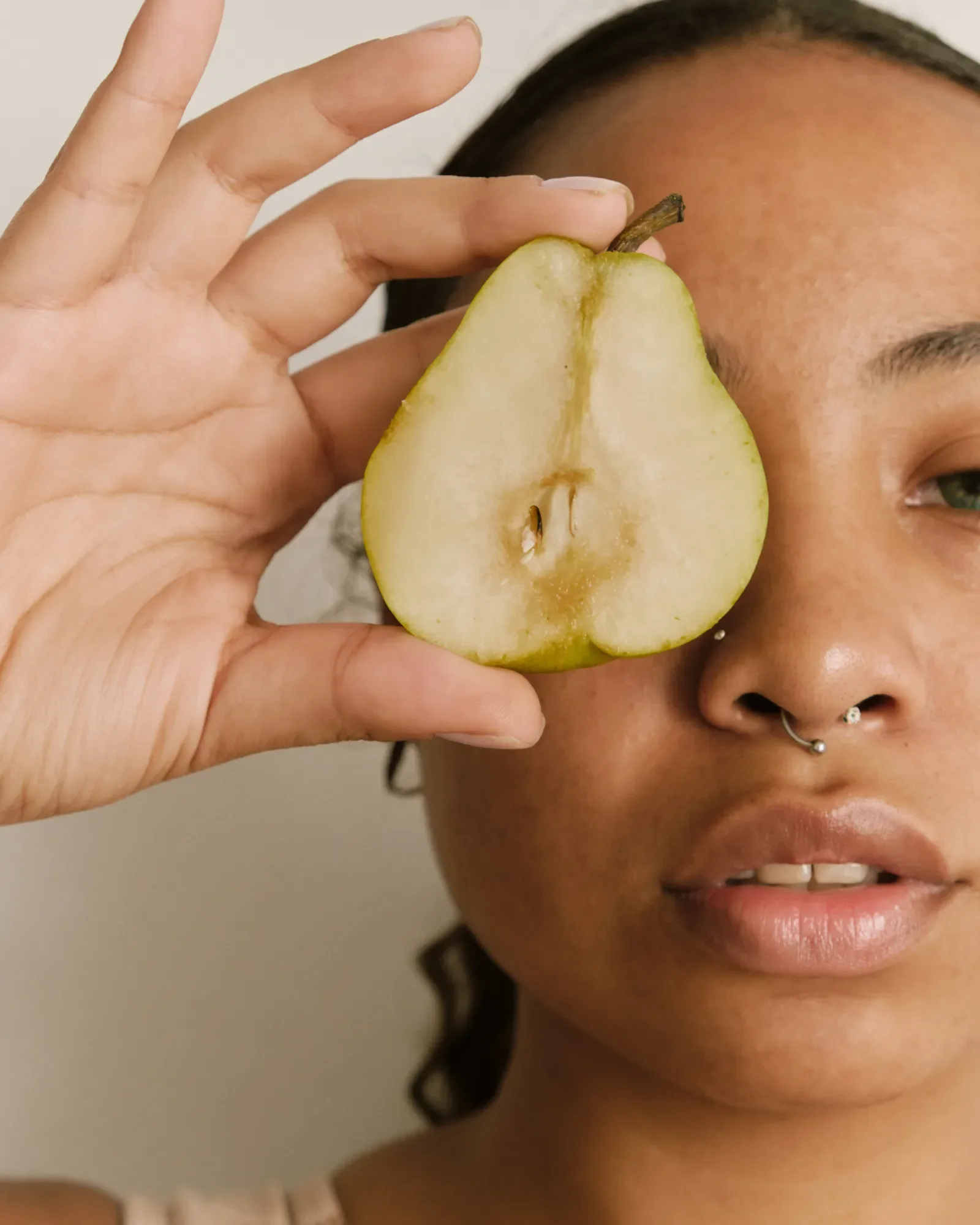 Portrait of a woman with half of a pear covering her eye