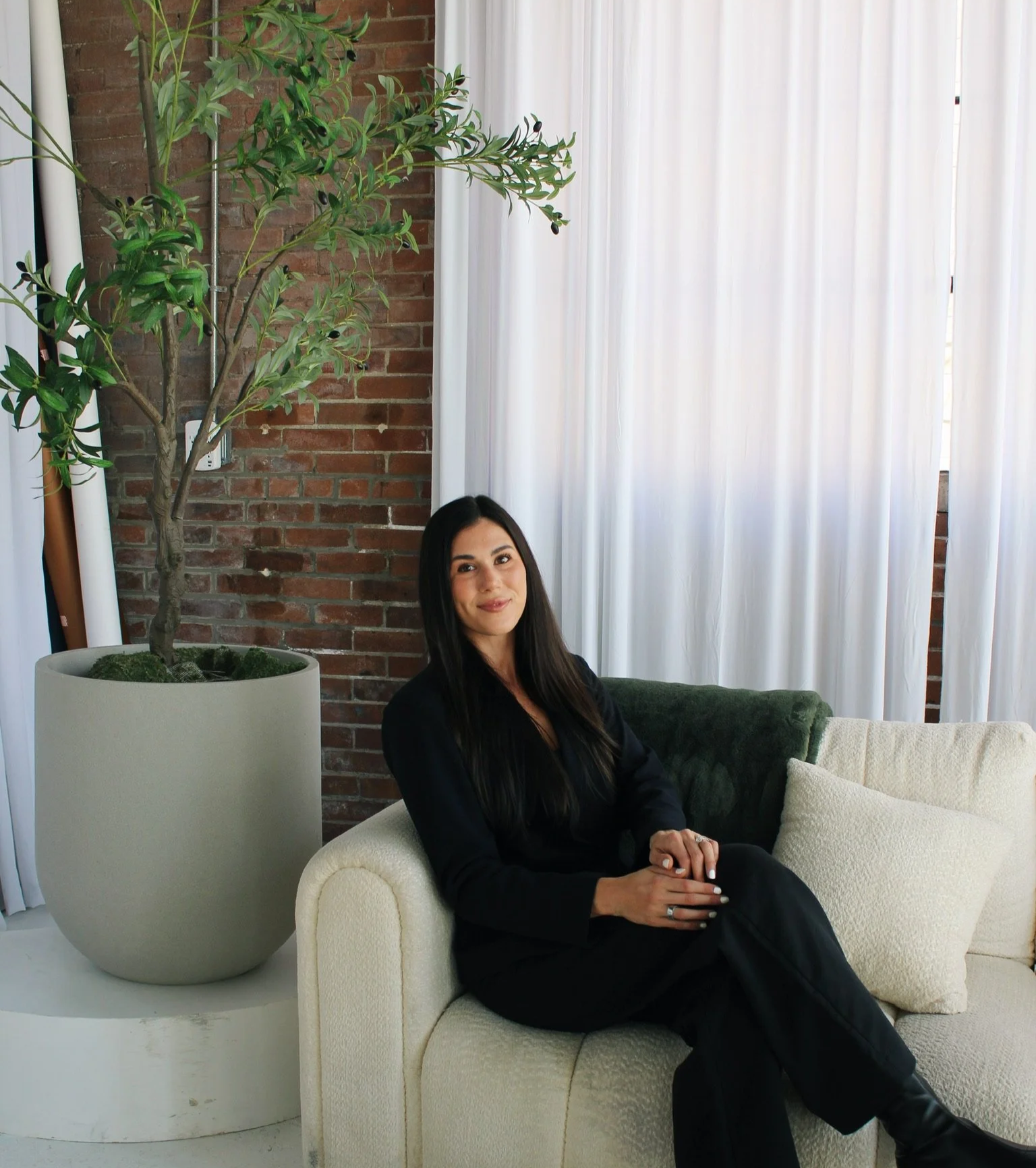 Kristen sitting on a white couch and smiling