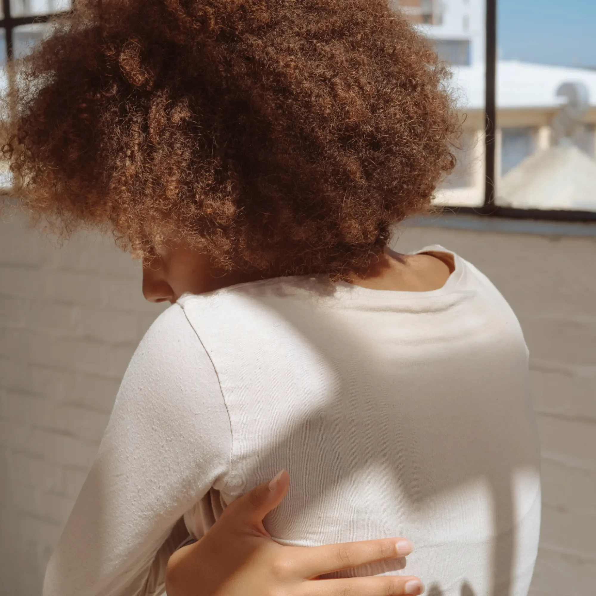Morose woman embracing herself in natural light