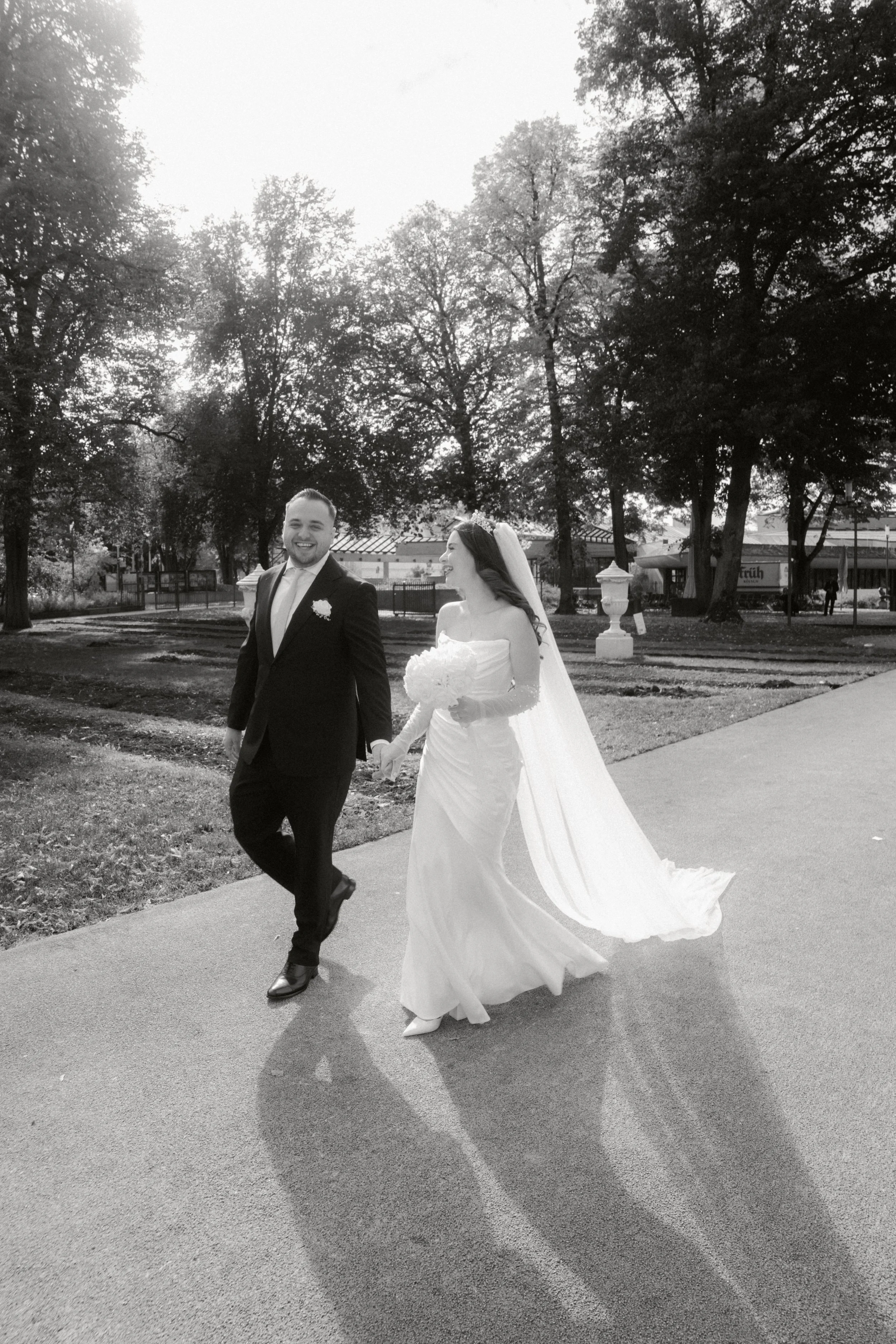 Bride and groom walking through a park after their wedding ceremony, photographed by Europe wedding photographer Änna Photography.

