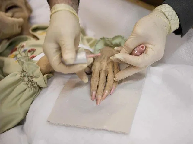 An up-close image of an embalmer putting nail polish on the deceased