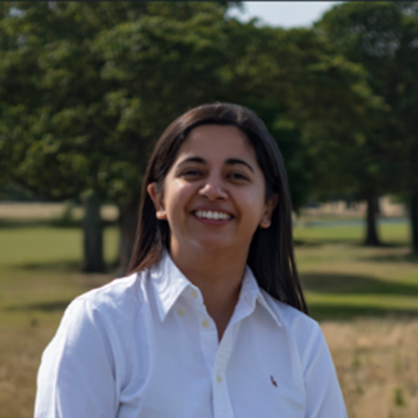 Sophia Ali, Wellcare Health, Beverley smiling outdoors in a park with green trees in the background.
