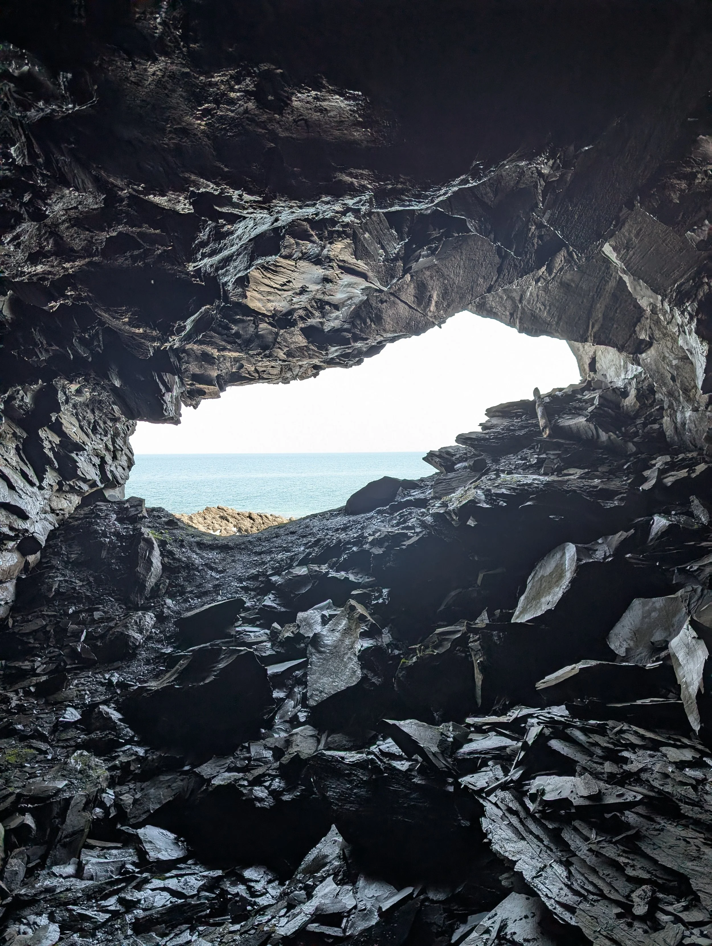 View from inside a rocky cave opening to the ocean through a natural arch