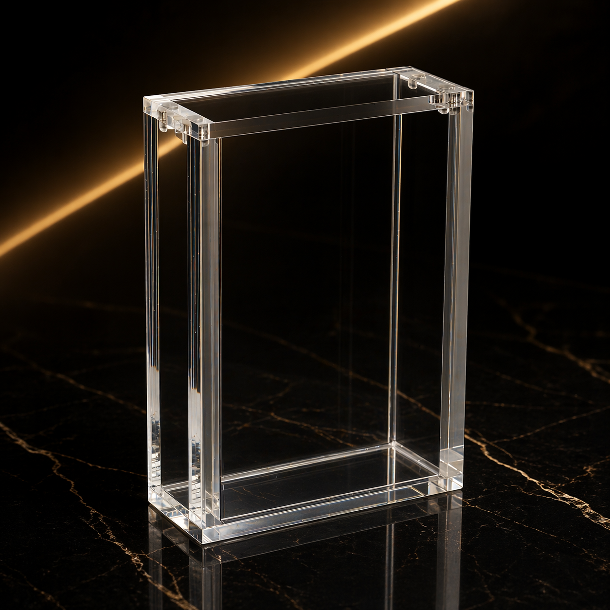 A clear glass or acrylic rectangular container with open top on a dark marble surface, with a dark background and a diagonal golden light streak.