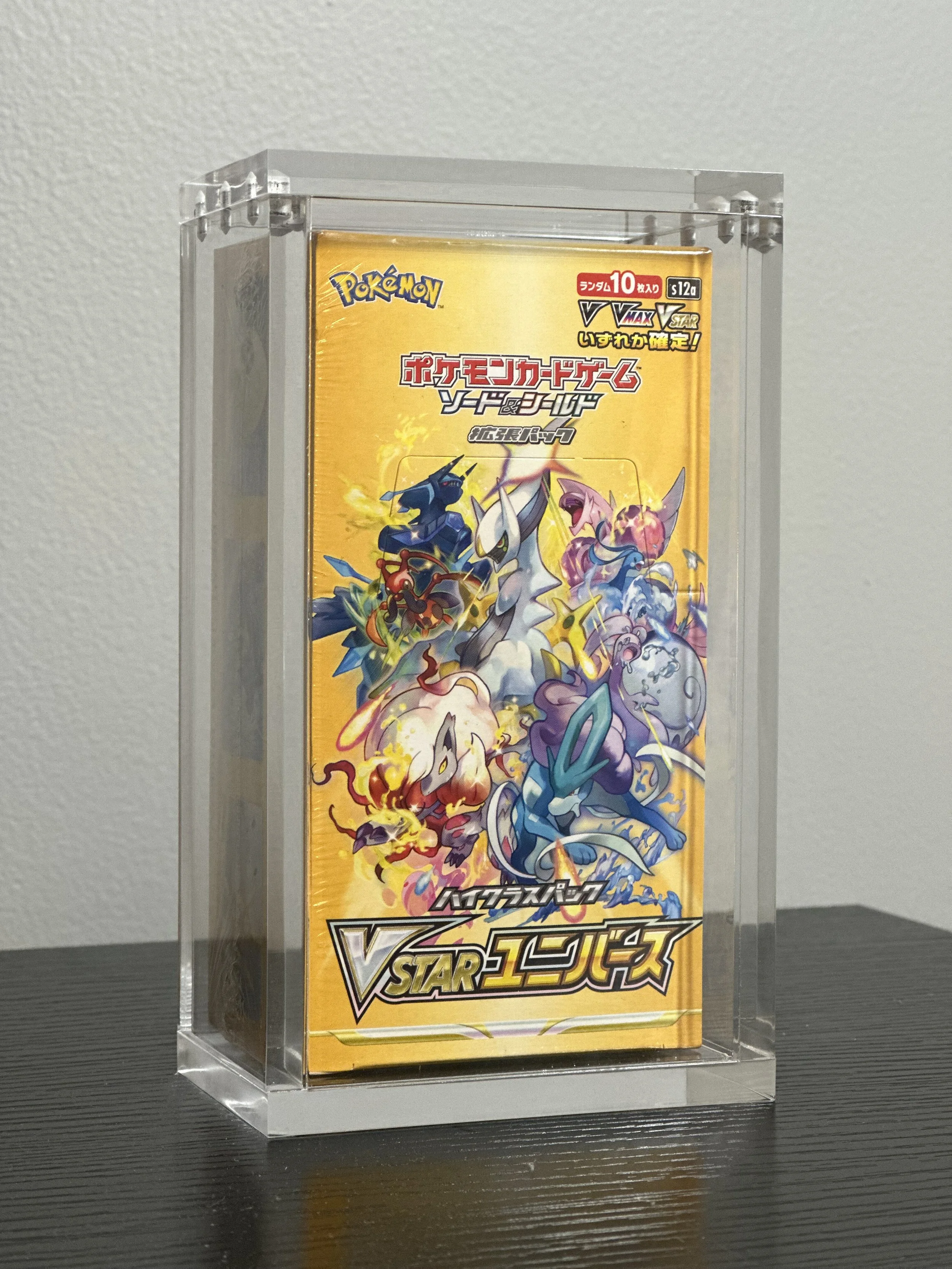 A sealed booster pack of Pokémon trading cards in a transparent display case.