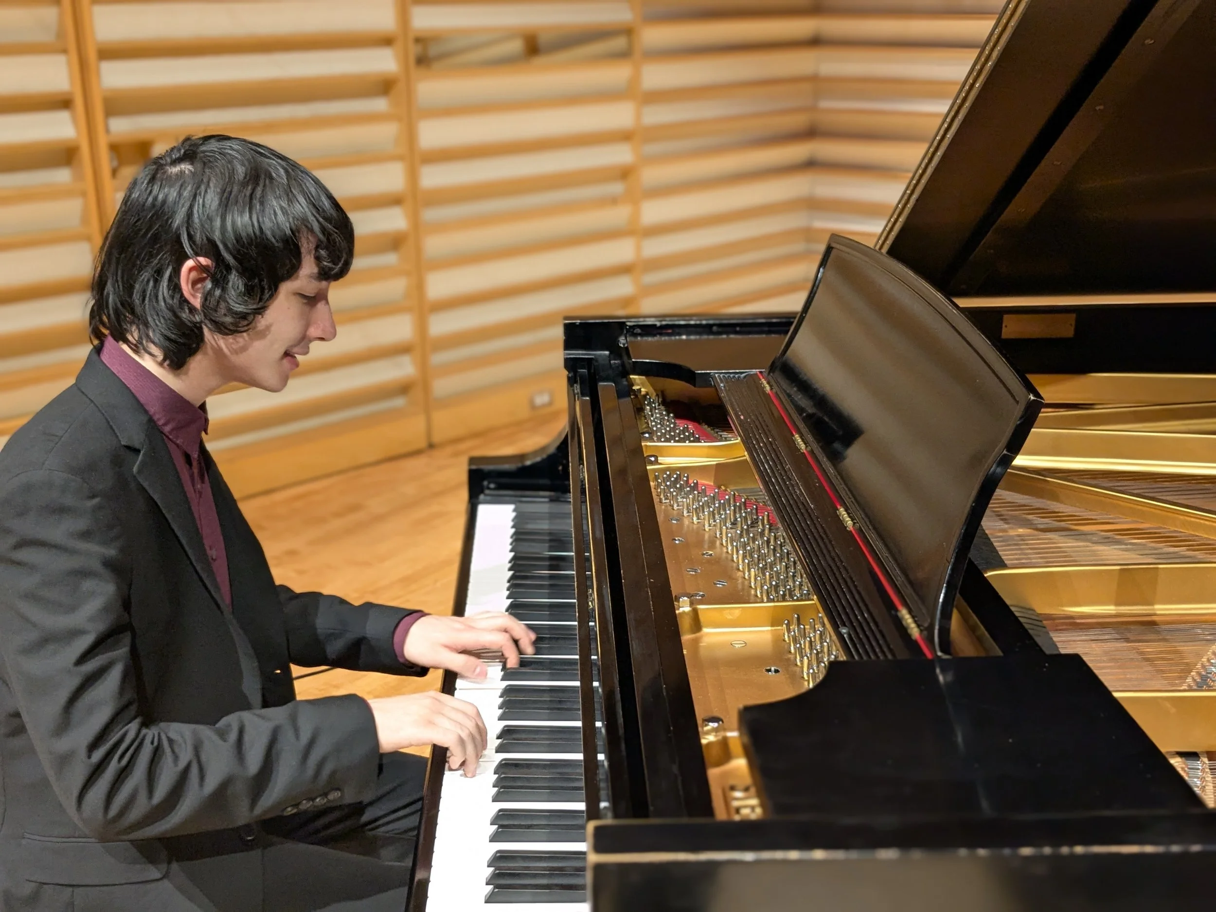 Jazz pianist Darwin Skalski performing on a grand piano in a recital hall