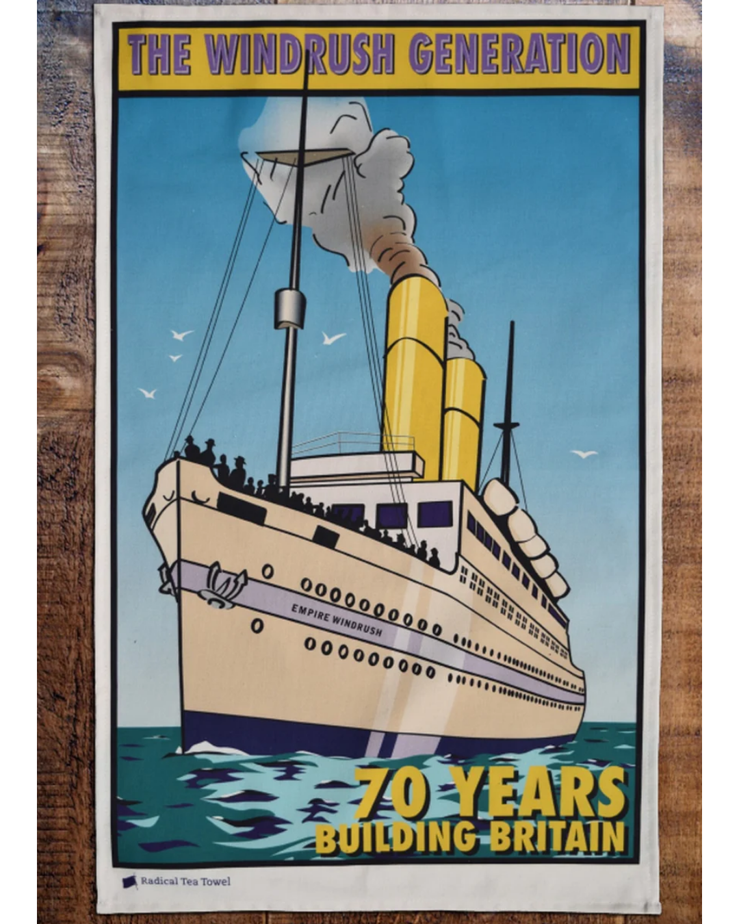Poster depicting a large historic ship named Empire Windrush with black smoke coming from its yellow smokestacks, celebrating 70 years of building Britain.