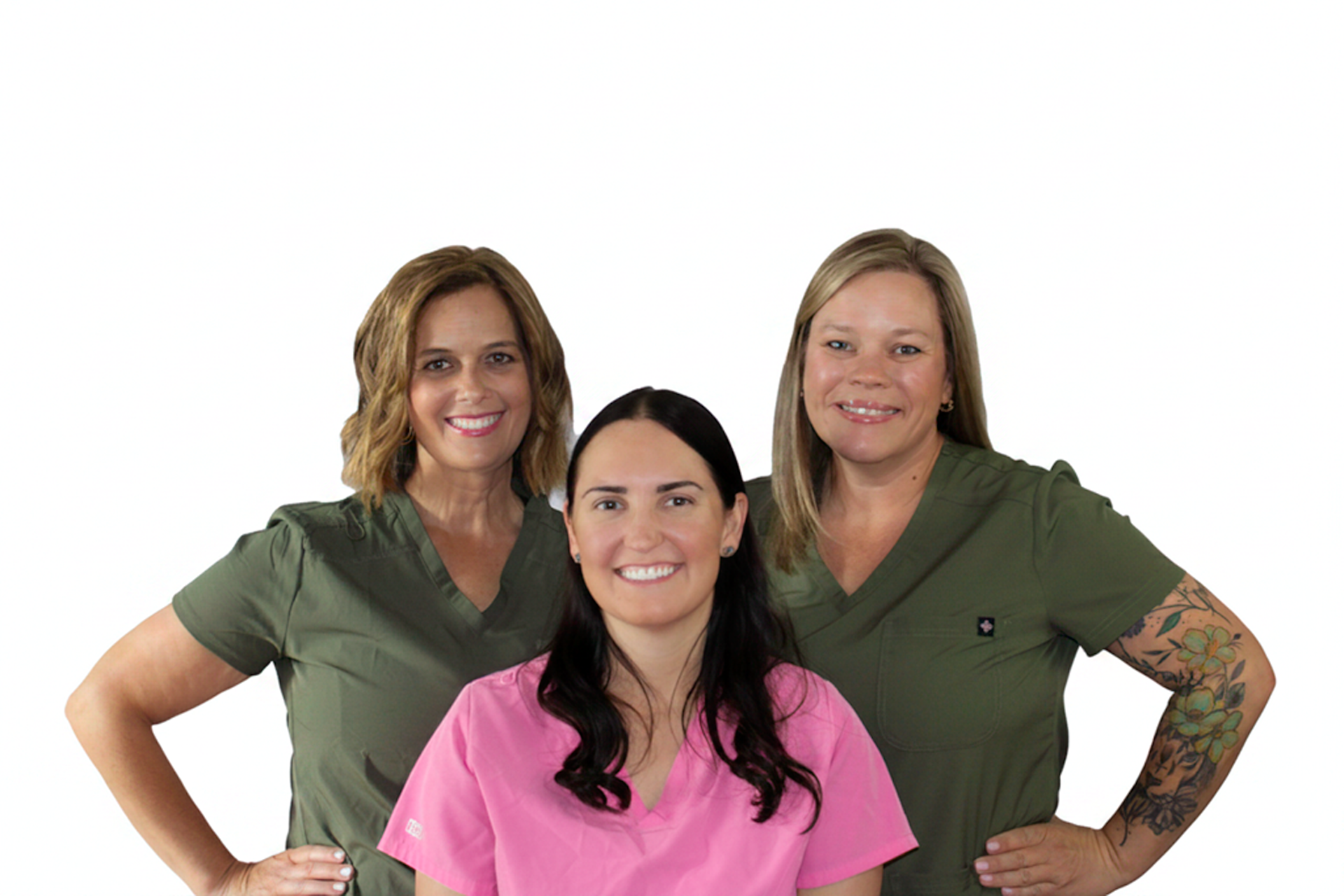 Four women dressed in medical scrubs smiling and posing together against a white background.
