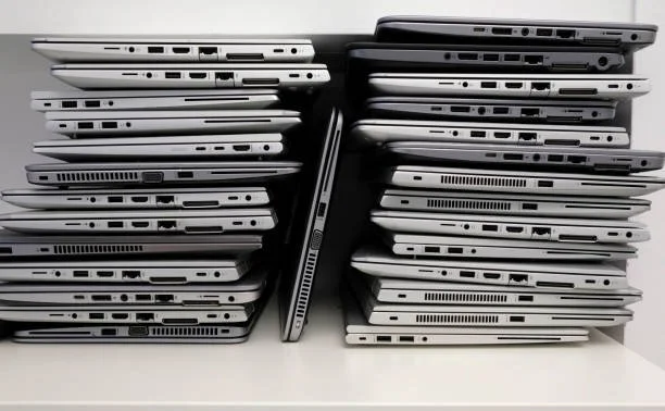 Stacked laptops arranged vertically and horizontally on a white surface.