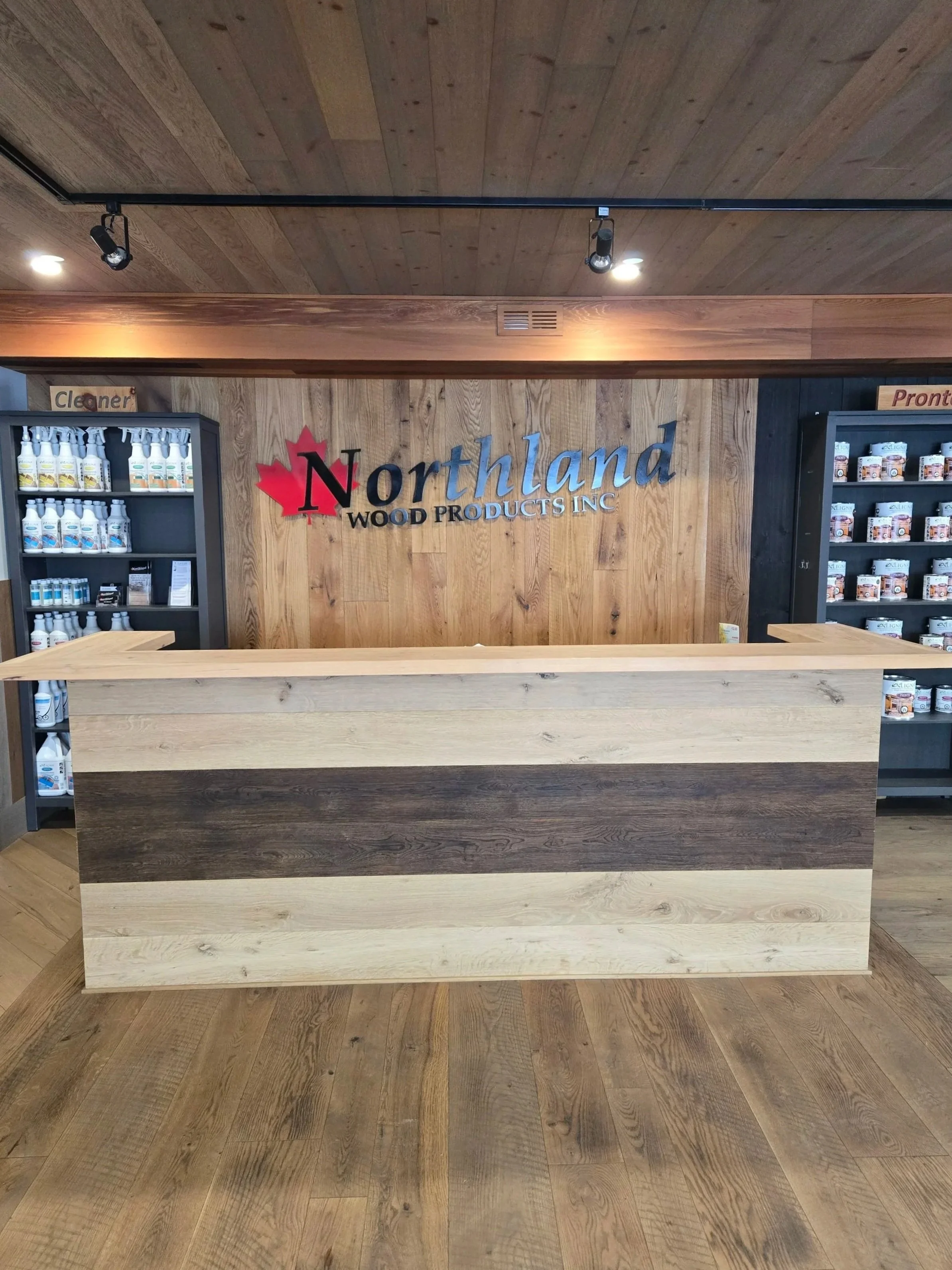 Wooden reception counter in Northland Wood Products Inc. store with shelves of wood care and cleaning products.
