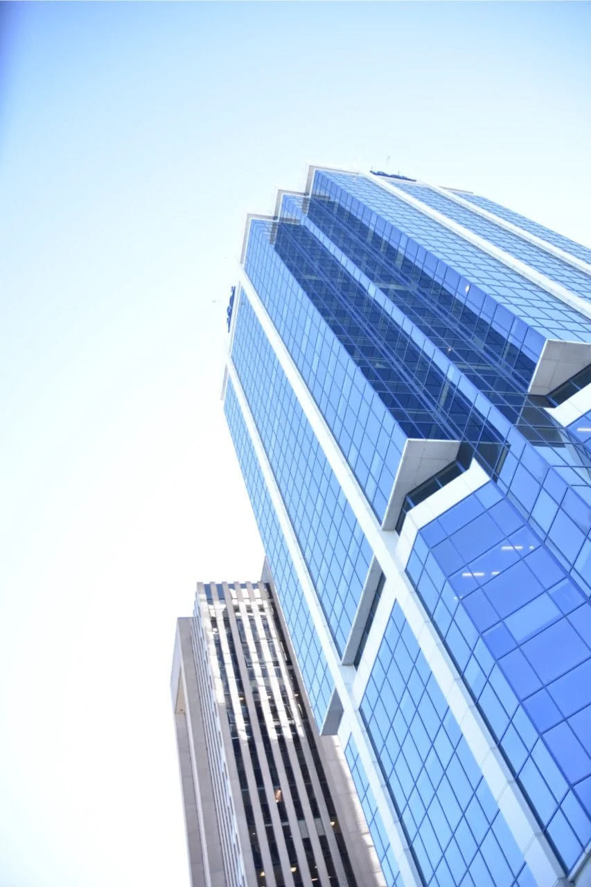 Tall modern skyscraper with blue glass windows in an urban cityscape.