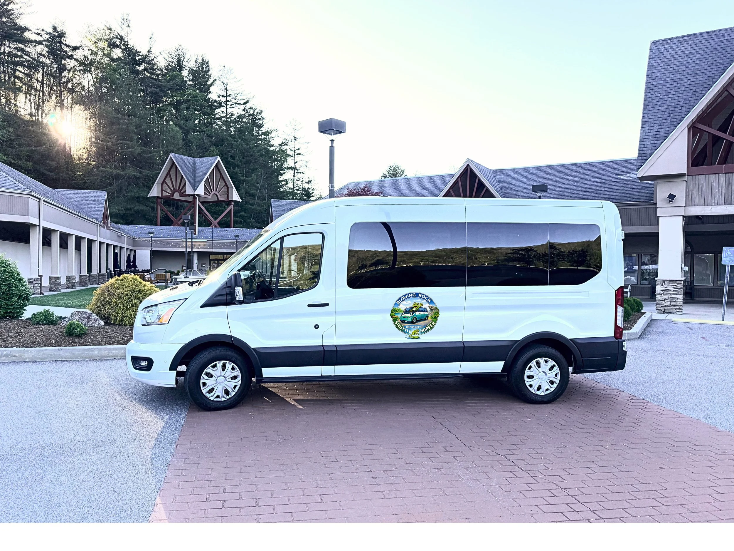 A white van with a logo of a frog and the text 'Blowing Rock Shuttle & Hopper' parked near Blowing Rock, NC.