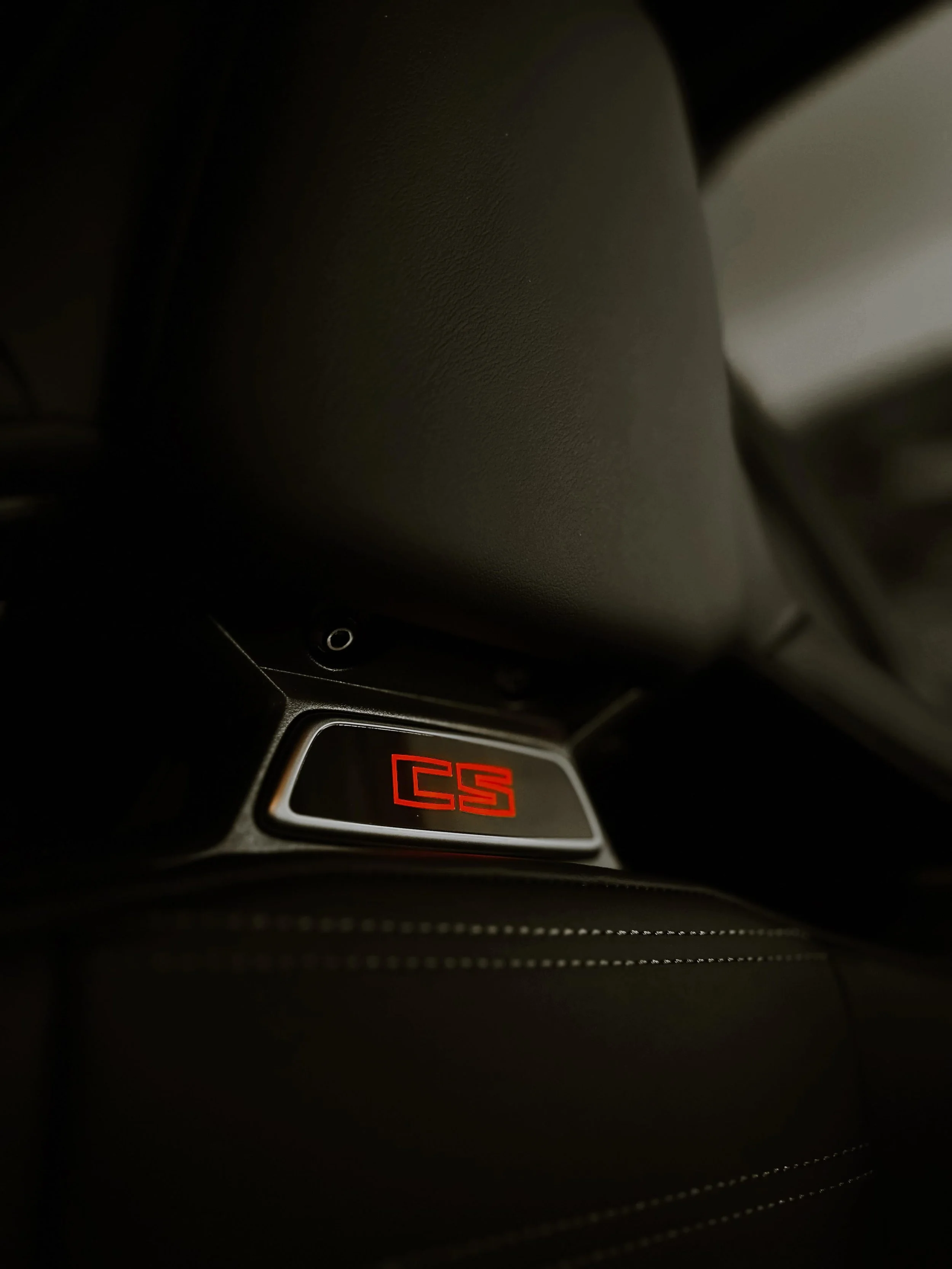 Close-up of a bucket seat with a red 'CS' logo illuminated.