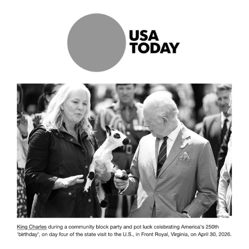 King Charles and Tracy Bloom holding a lamb at a community event with a crowd in the background in front of a USA Today sign.