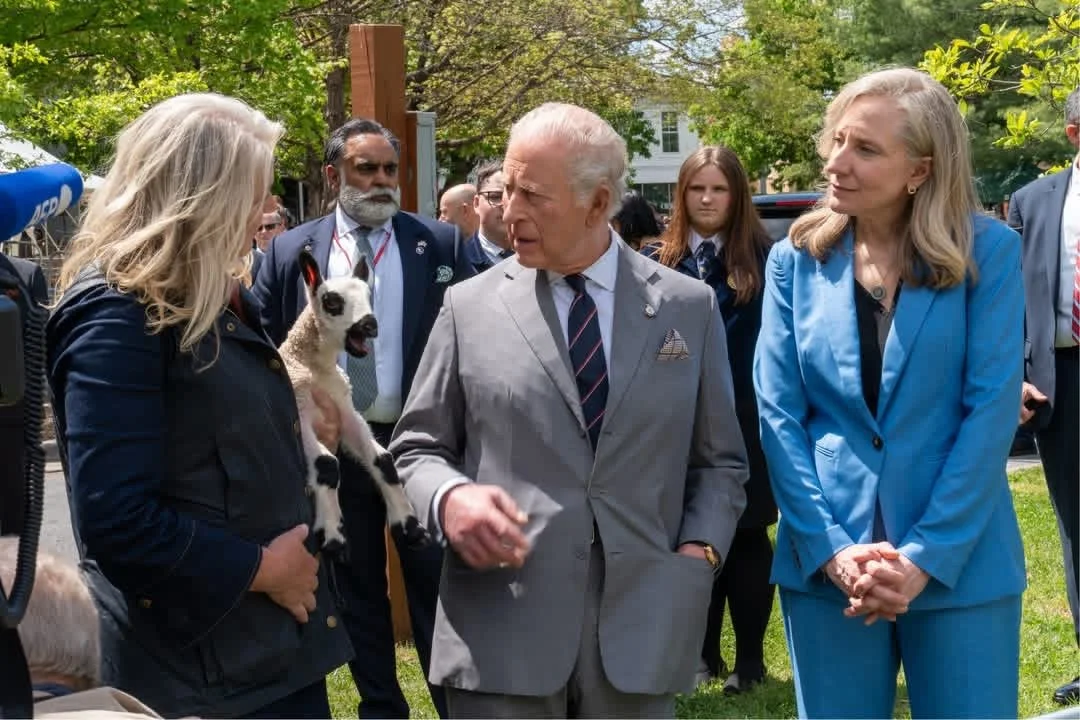 Tracy Bloom holding a lamb talking with His Majesty King Charles III.