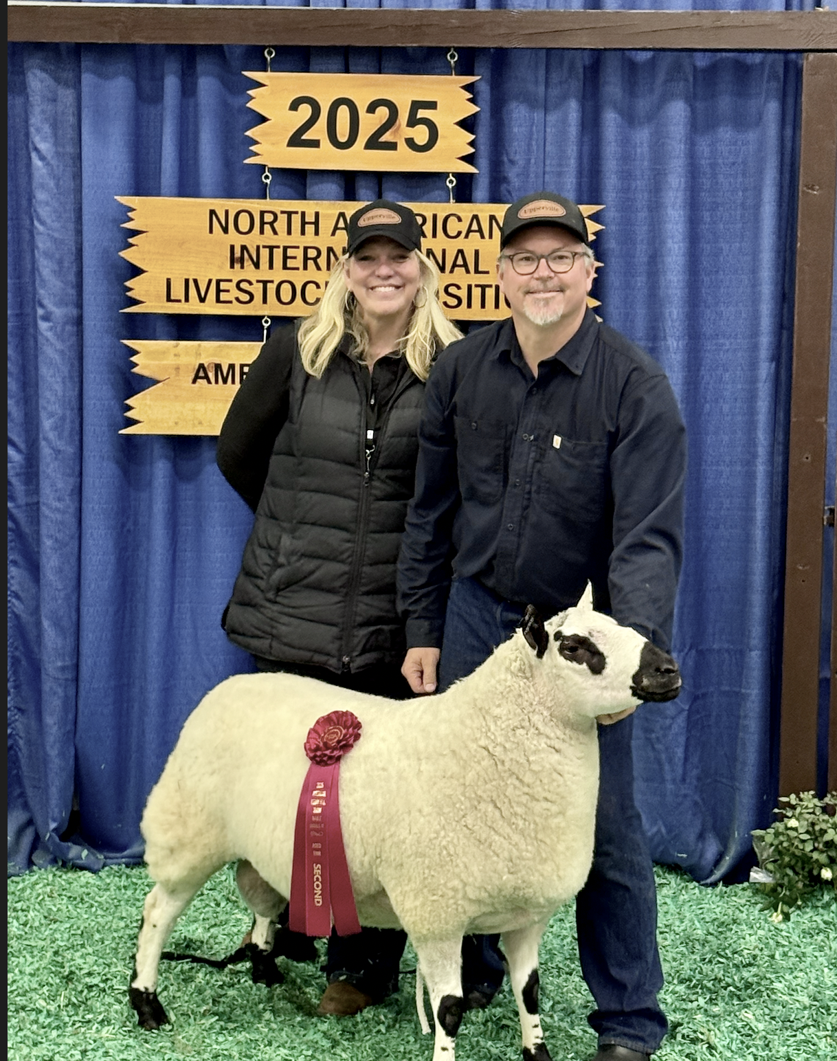 Tracy Bloom and her husband, at the North American International Livestock Exhibition in 2025, with a blue curtain backdrop.