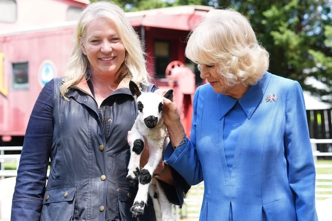 Tracy Bloom holding a lamb talking with Her Majesty Queen Camilla.