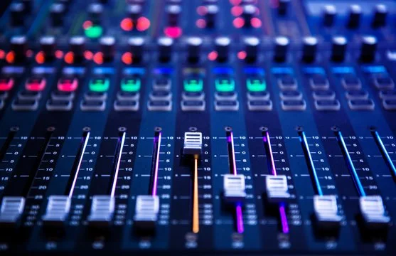 Close-up of an audio mixing console with colorful sliders and knobs.