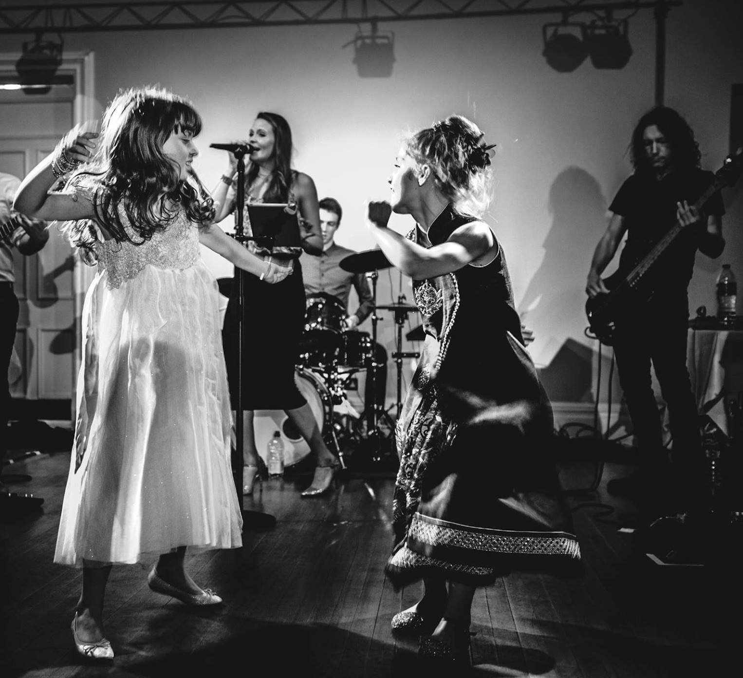 Kay Acoustic live wedding performance singing with a band while children dance in front during a family-friendly UK event.