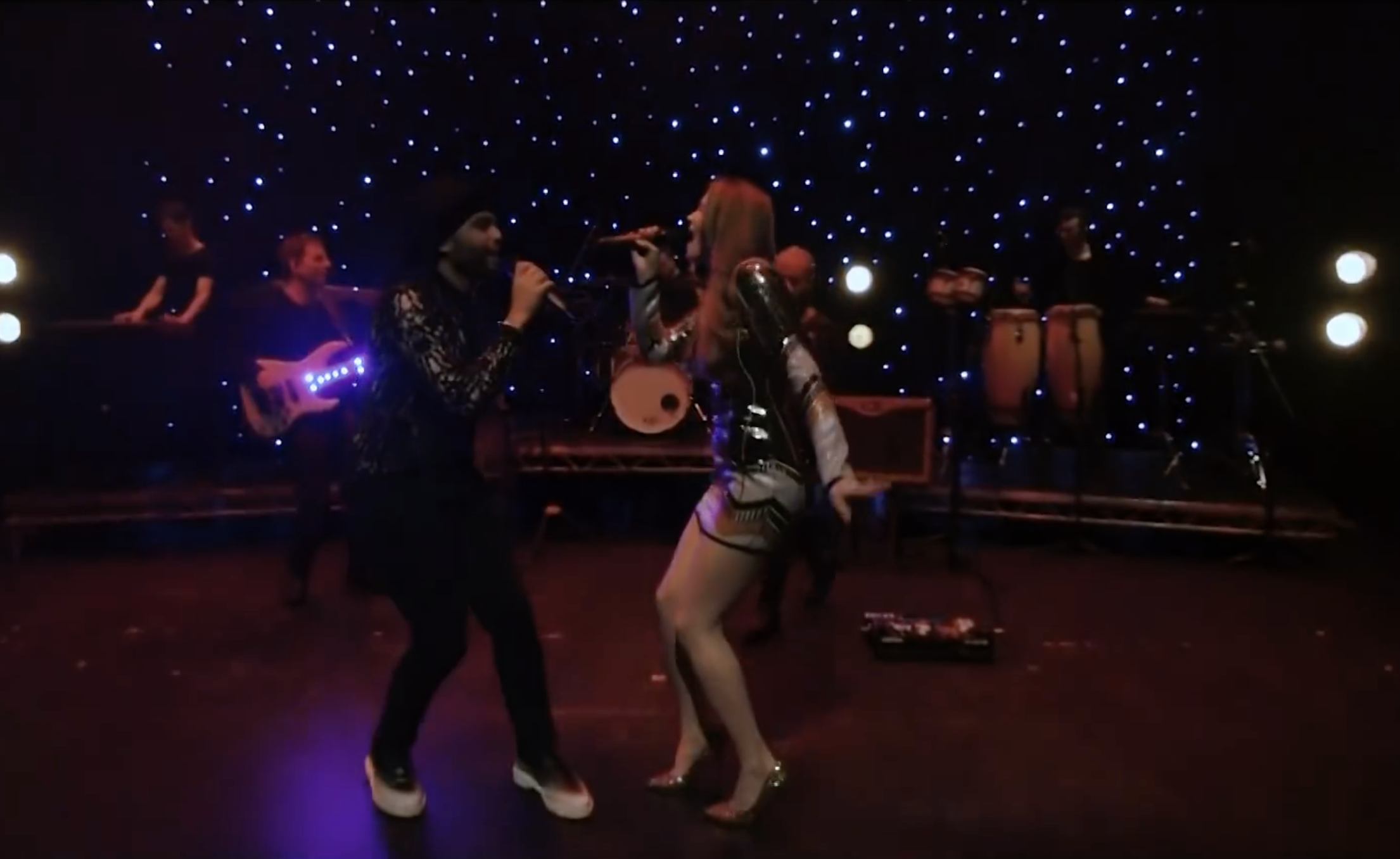Kay Acoustic performing on a theatre stage with a featured singer in a professional music video for live acoustic music and event entertainment.