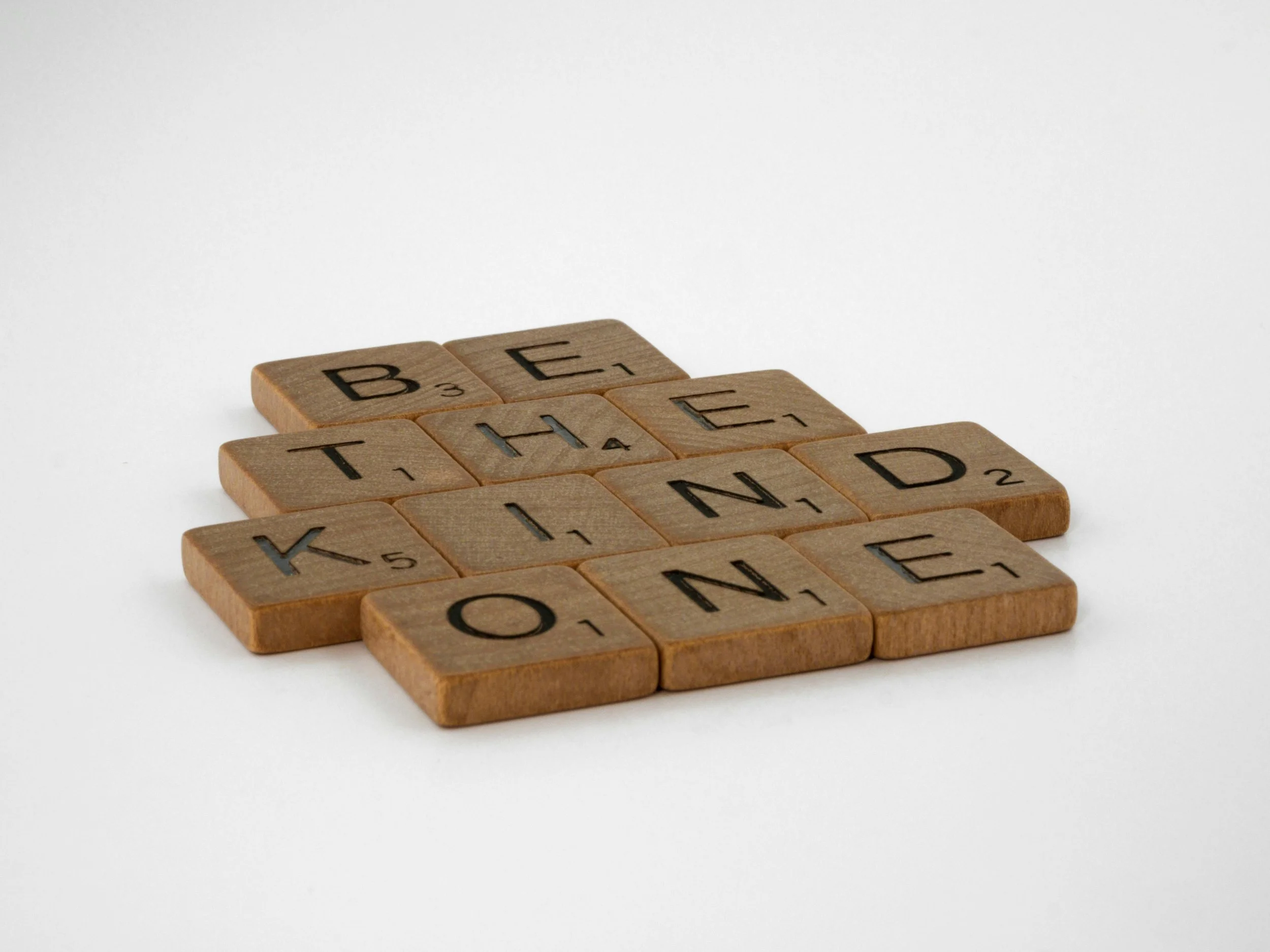 Scrabble tiles spelling out 'Be The KIN, D, ONE' on a white background.