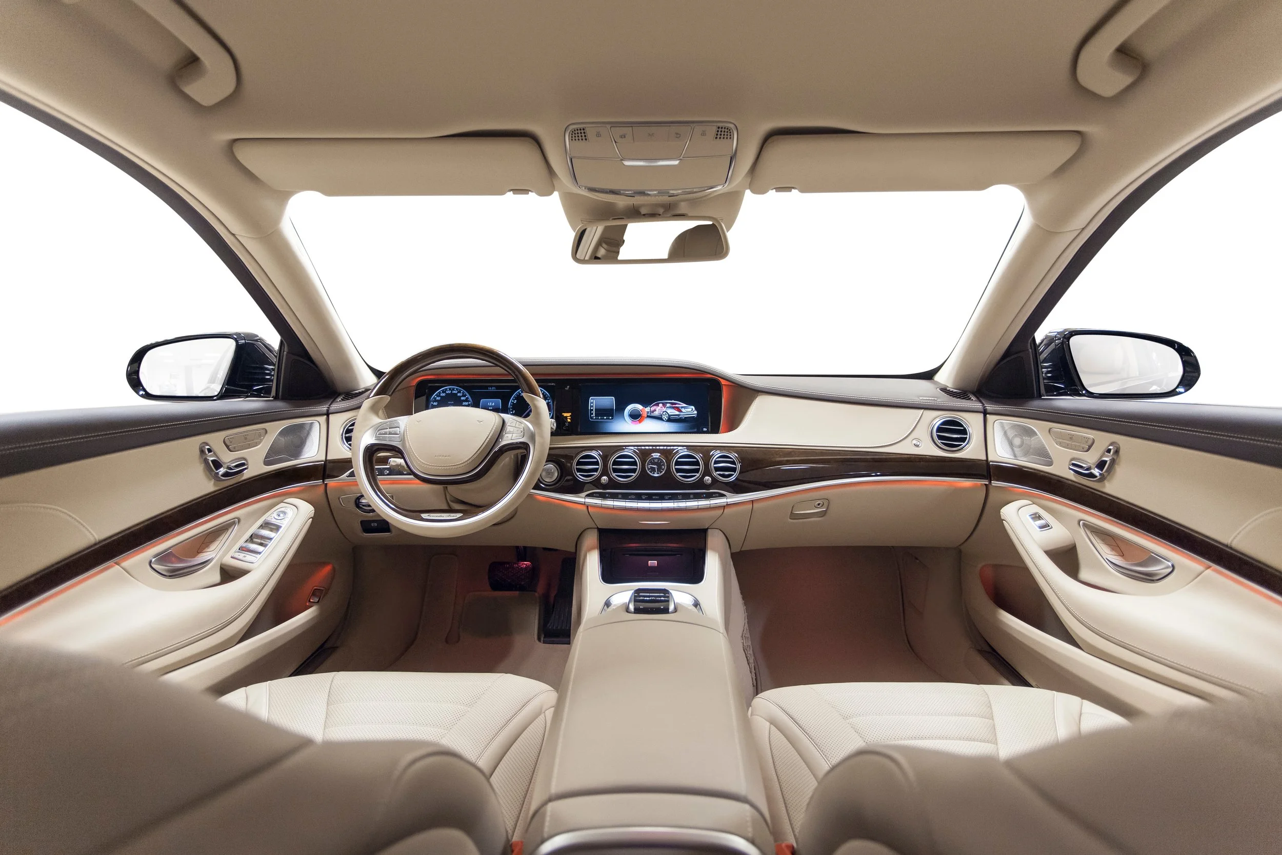 Interior view of a luxury car showing a dashboard with a digital display, beige seats, and wood trim accents.