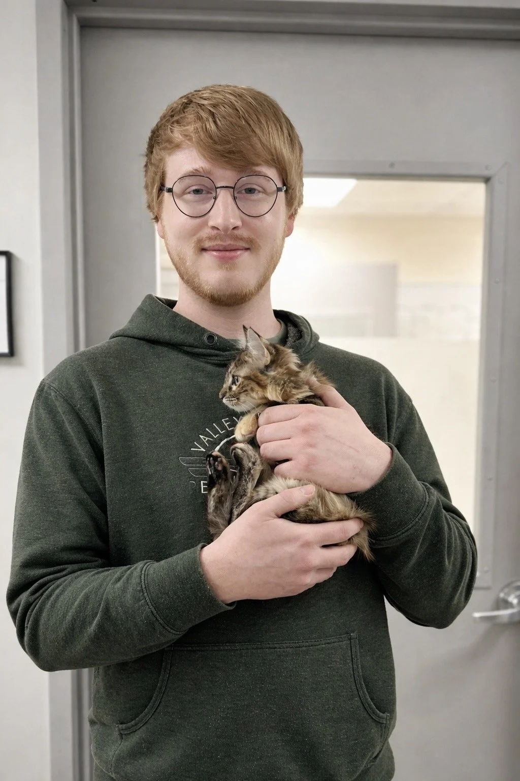 A man man  holding a small tabby kitten.