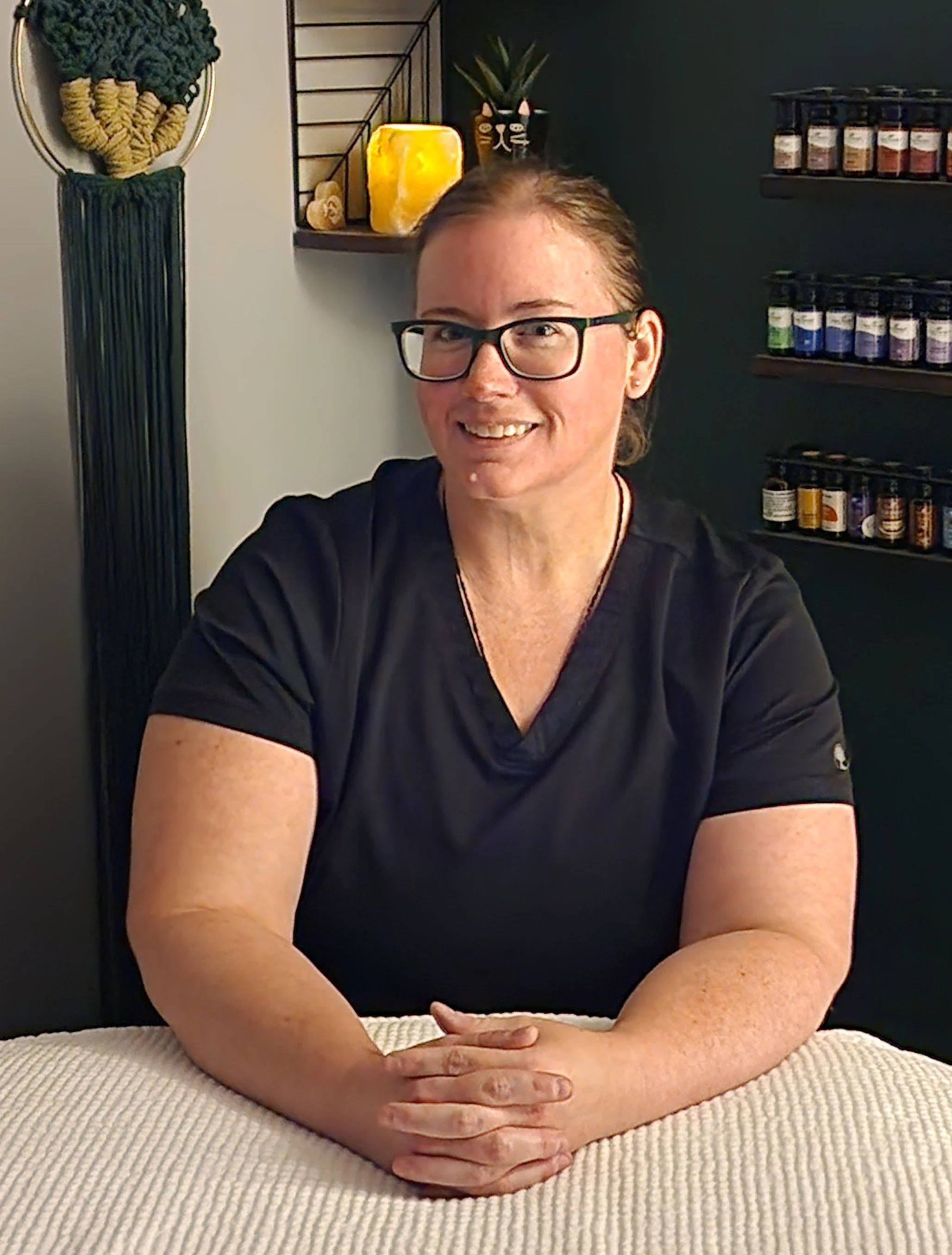 Erika smiling while seated at her massage table.
