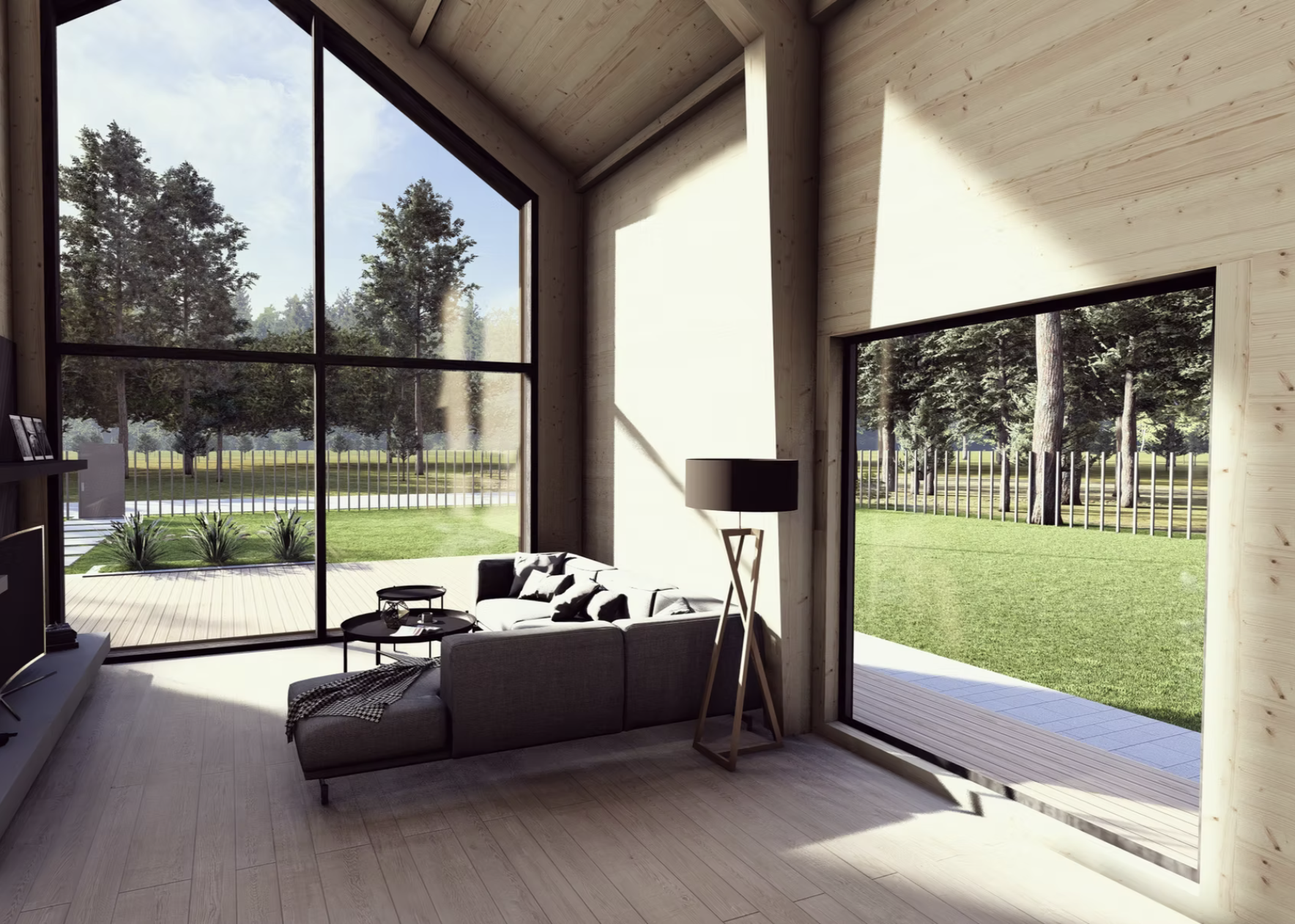 Interior view of a modern living room with large floor-to-ceiling windows showing a grassy yard and trees outside, a gray sofa with black and white pillows, a black floor lamp, a small side table, and light wood flooring and walls.