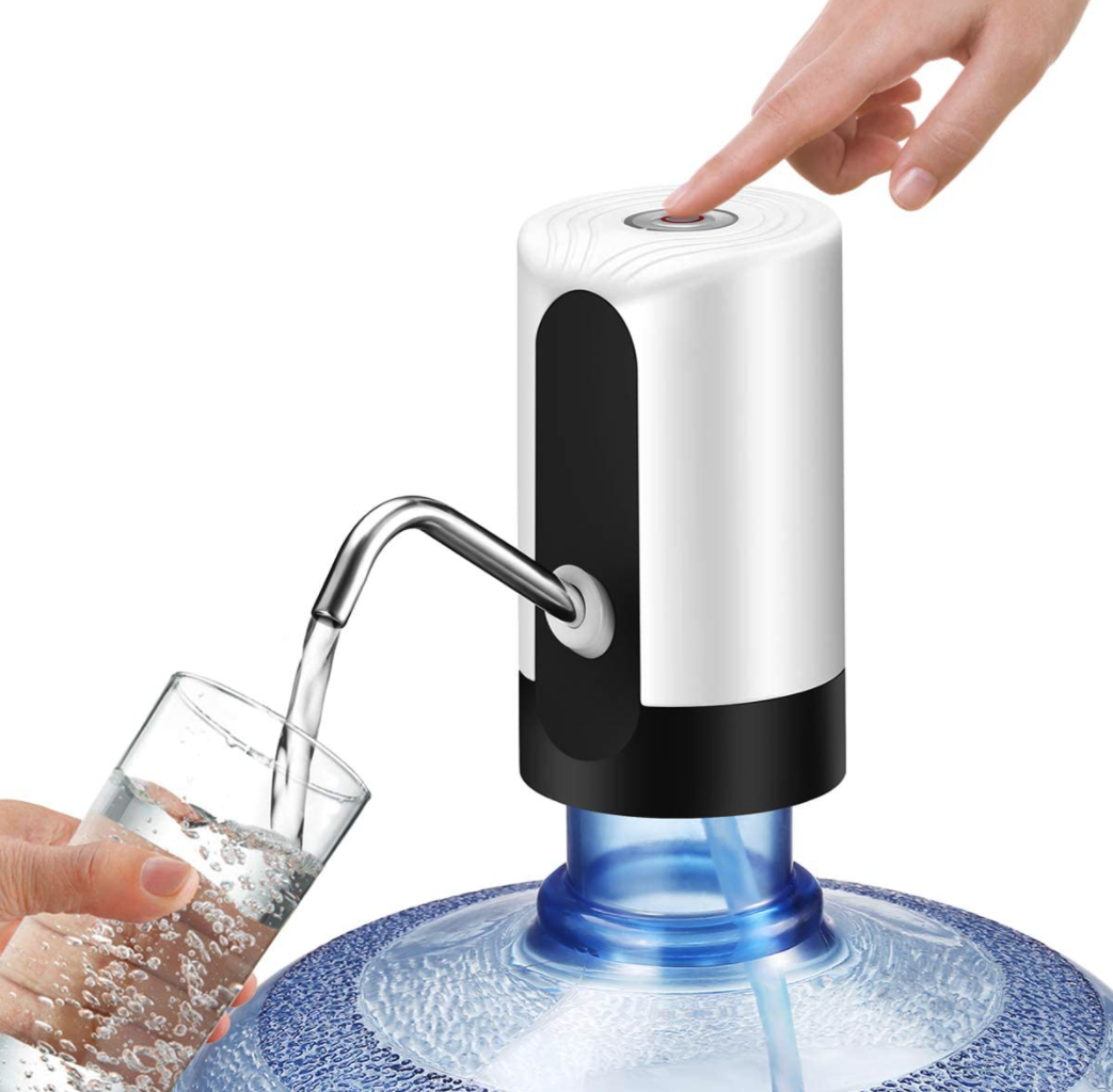 Eine Hand drückt einen Knopf an einer weissen Trinkwasserpumpe. Wasser wird in ein Glas gefüllt, das von einer anderen Hand gehalten wird.