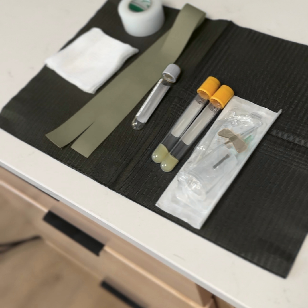 Laboratory testing kit with test tubes, swabs, and tape on a black mat.