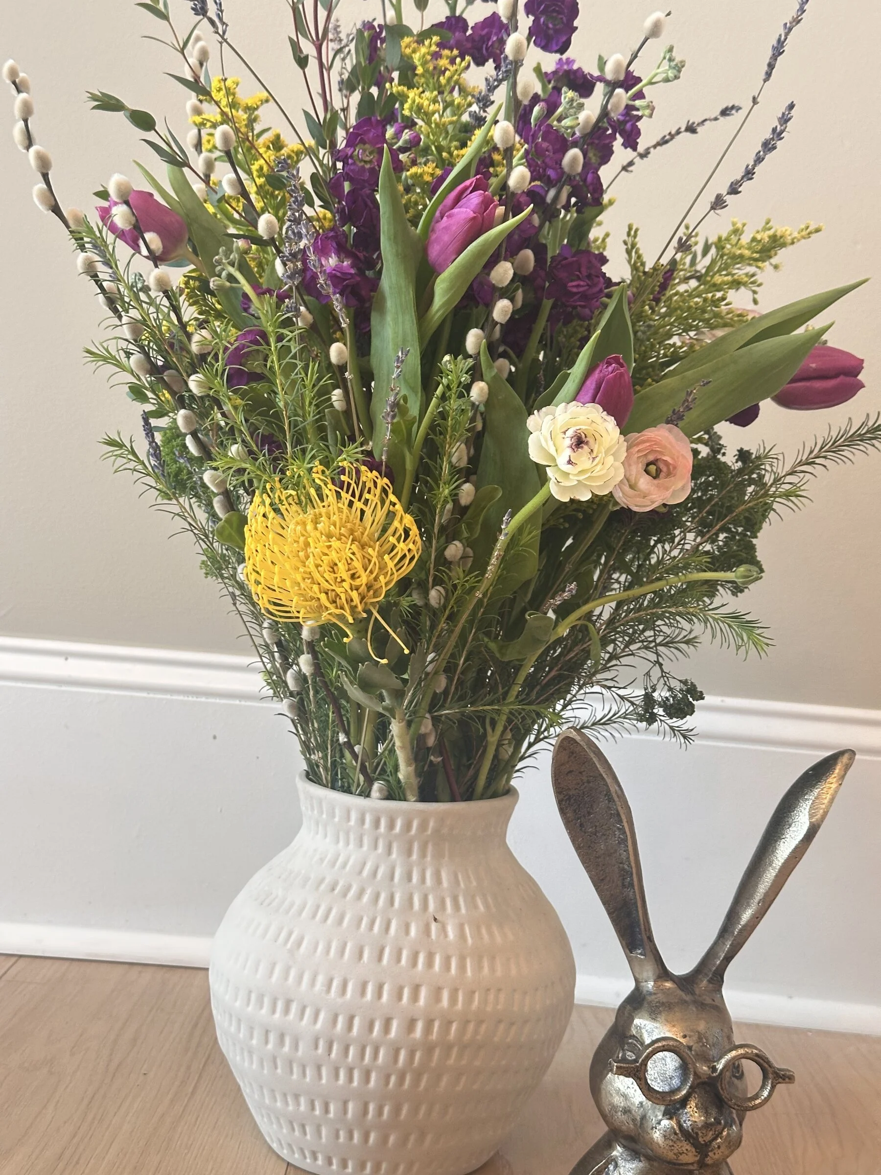 Yellow pincushion protea and purple tulip arrangement in a white textured vase with pussy willow, Botanical Studio by Kelly Eileen