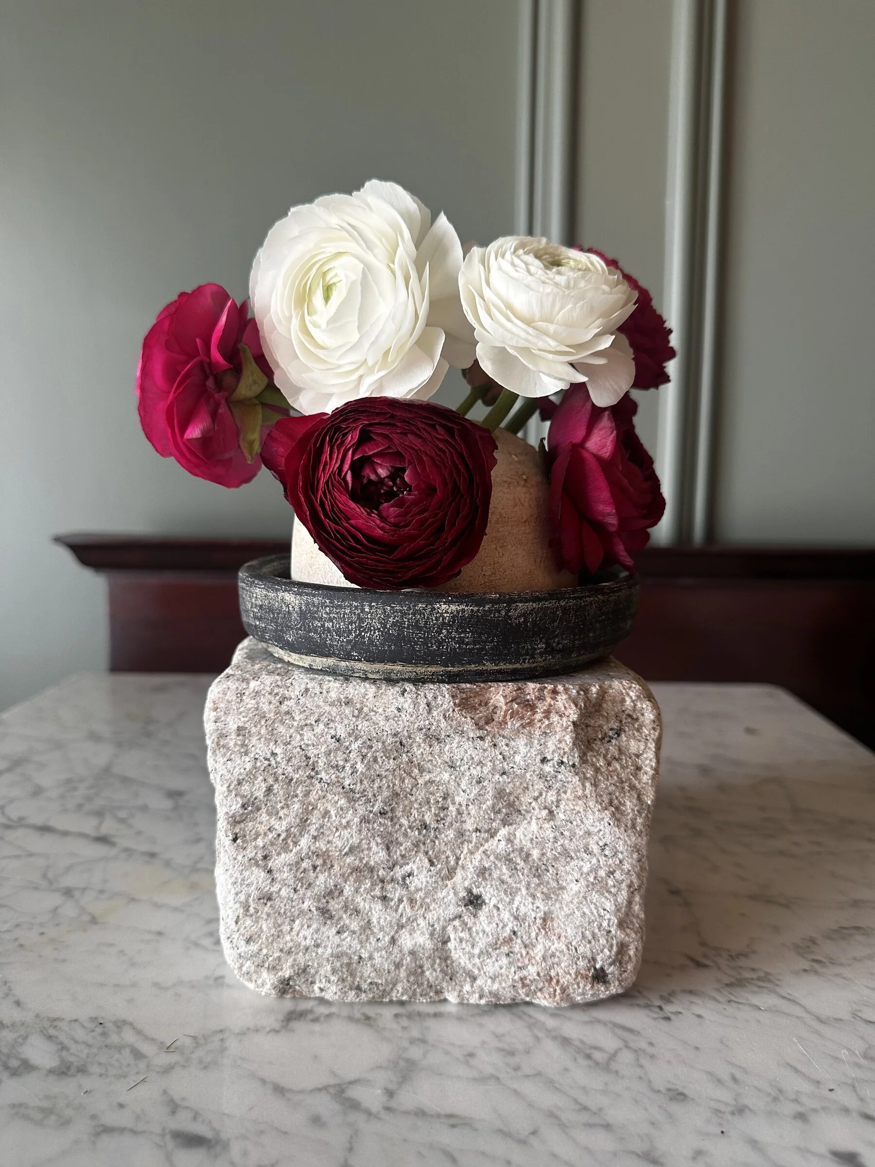 Ceramic Frog on top of a granite base, filled with red and white ranunculus.
