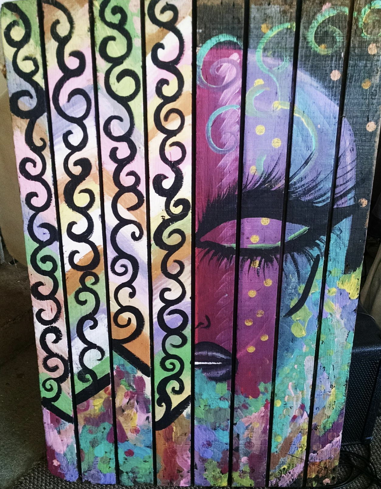 Colorful abstract painting on wooden slats depicting a large eye with purple eyeshadow, long eyelashes, and colorful swirling accents.