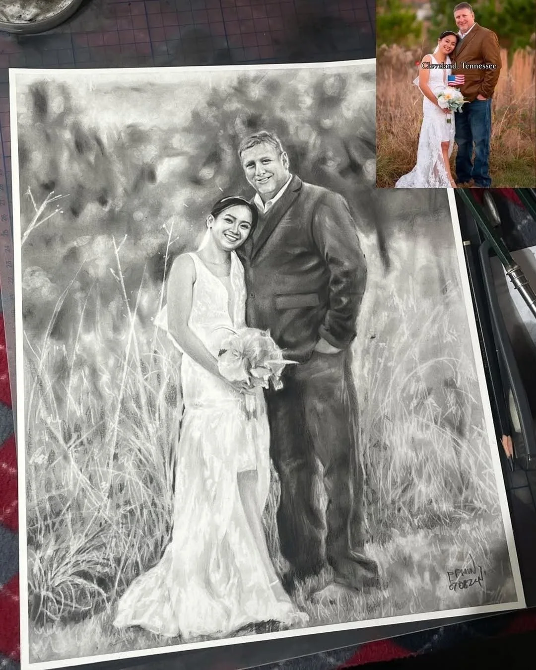 Black and white portrait of a smiling couple in wedding attire, standing in a field with tall grass, outdoors.